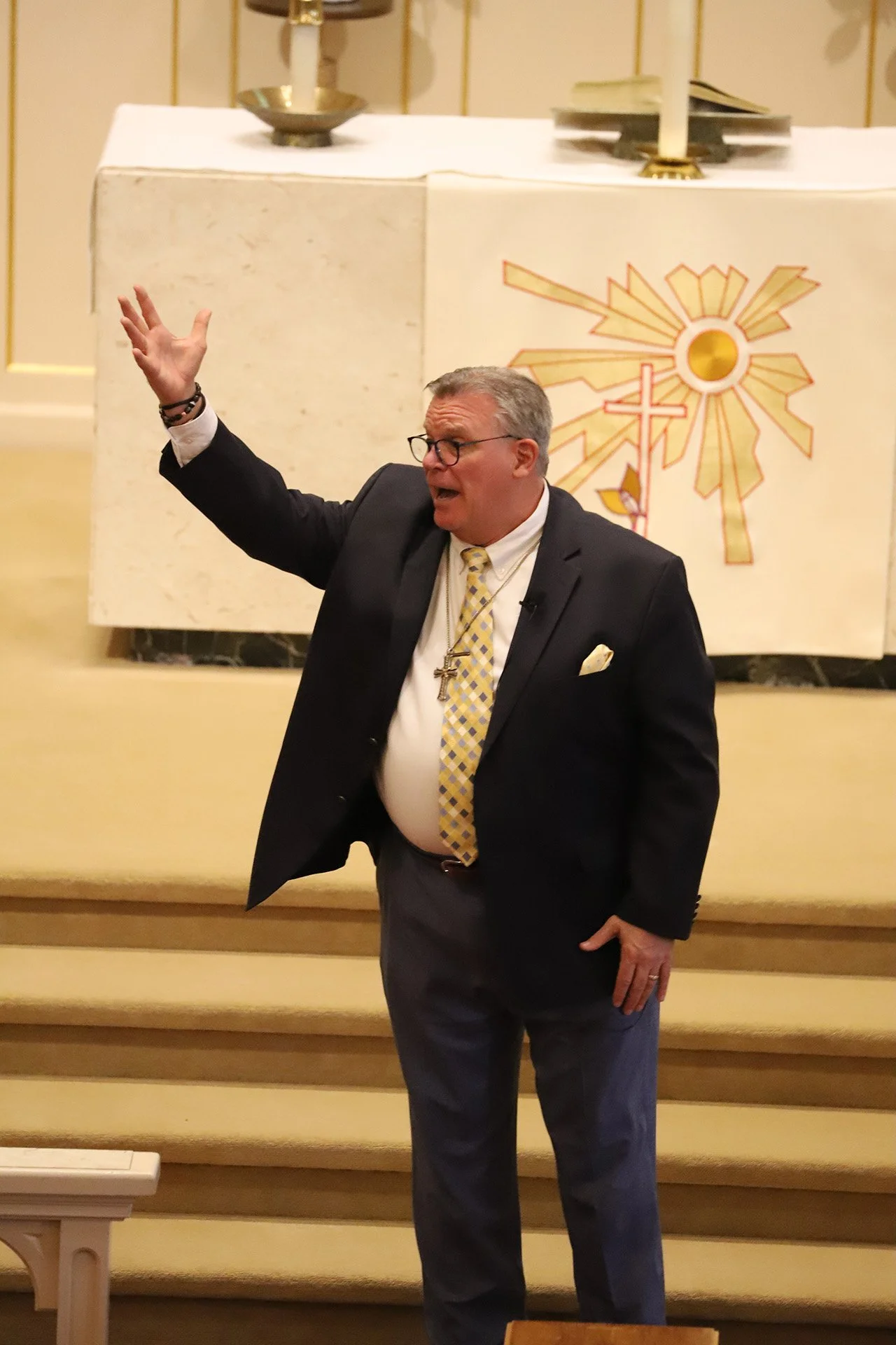 Senior Pastor at Immanuel, Pastor Yonker, standing in front of an altar with his right hand raised, addressing the congregation.