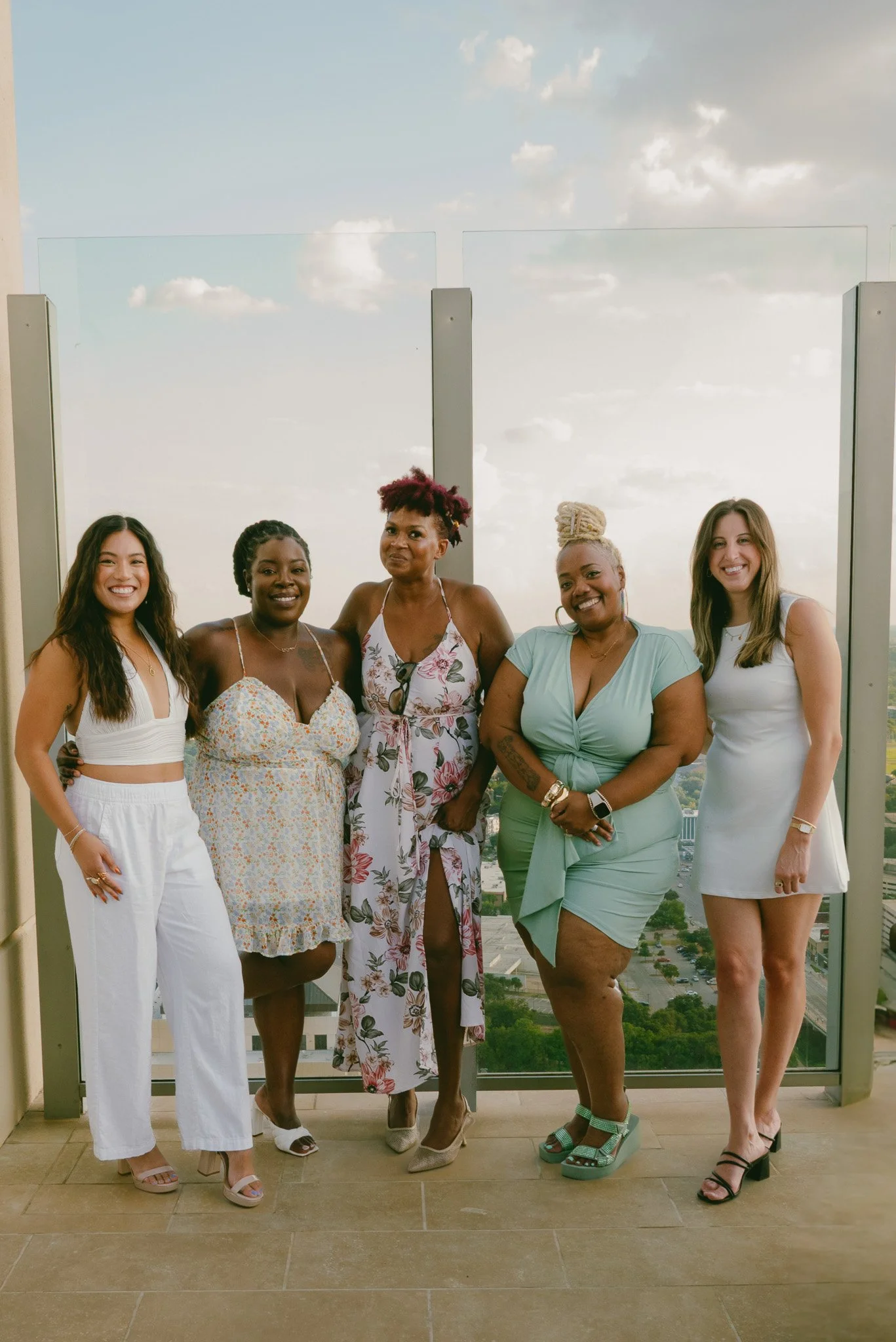 A group of women wearing chic spring dresses in solid white, solid green and floral patterns.