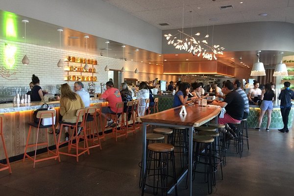 People sitting at a modern bar and counter inside a restaurant, dining and socializing.