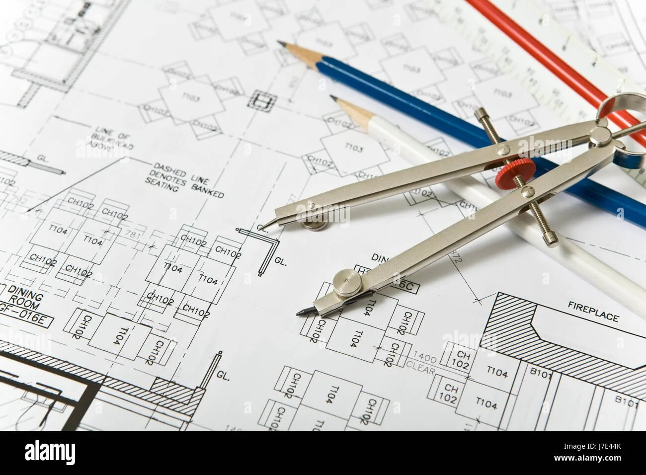 Architectural blueprint with drawing tools including a compass, pencils, and rulers.