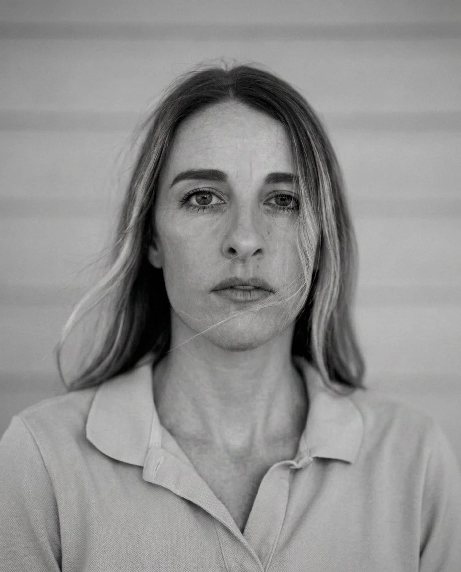 Black and white close-up portrait of a woman with medium-length hair, wearing a collared shirt, looking directly at the camera with a serious expression.