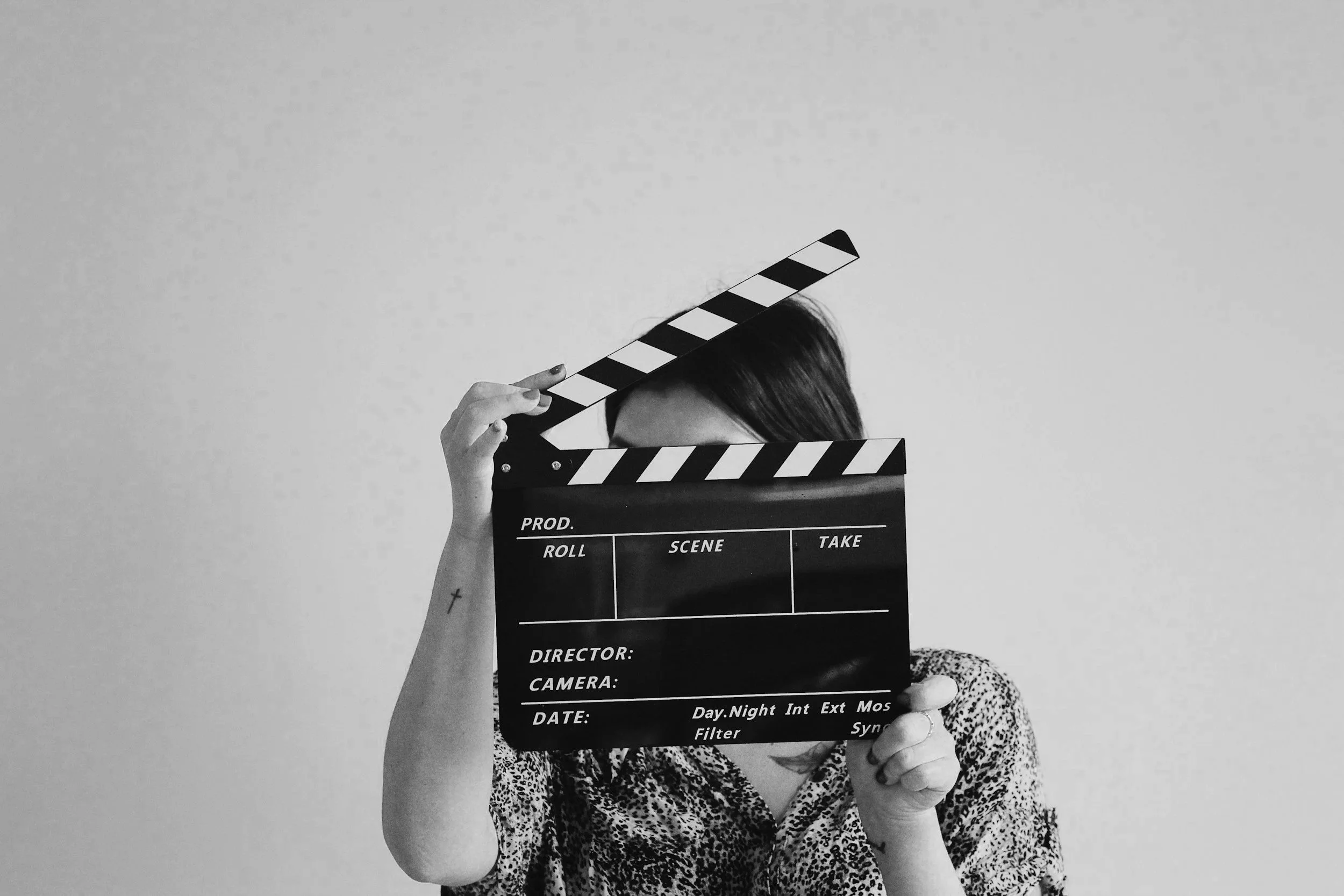 Person holding a clapperboard in front of their face, with only part of their head visible.