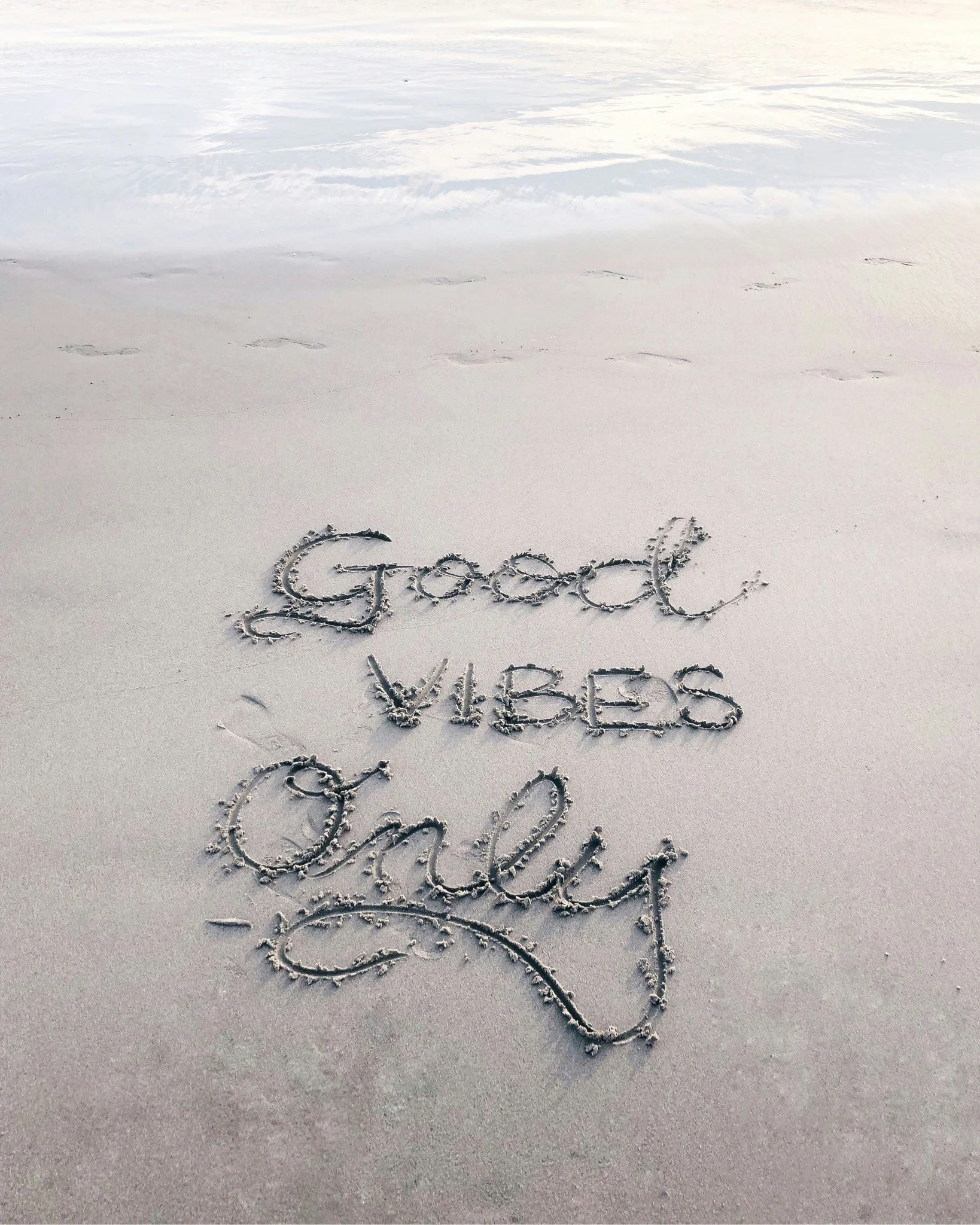 Message written in the sand on a beach, saying "Good Vibes Only".