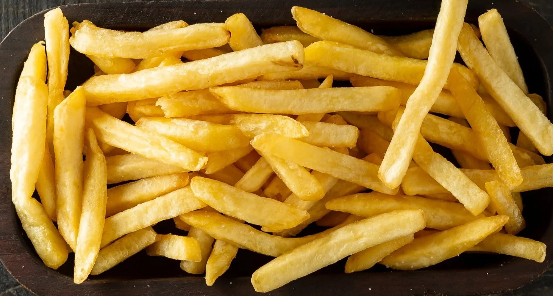 A black dish filled with golden French fries.