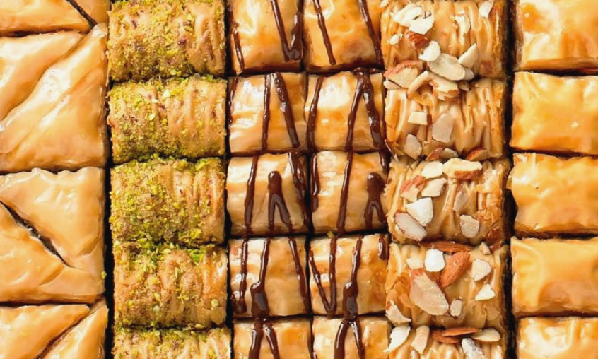 Assorted Middle Eastern baklava with different toppings including pistachios, chocolate drizzle, and chopped almonds.