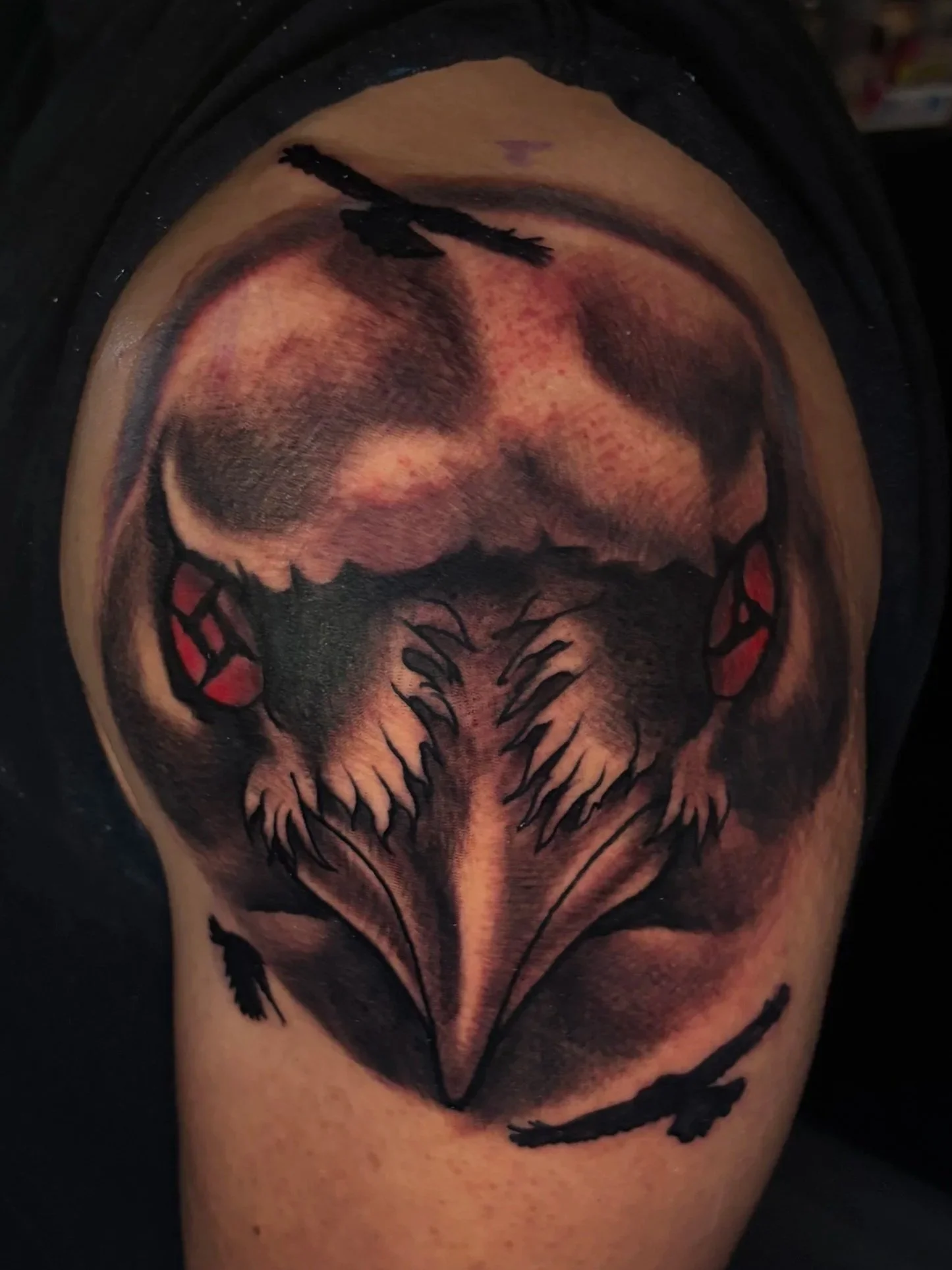 Tattoo of a crow's face with detailed shading on the face and Itachi eyes
