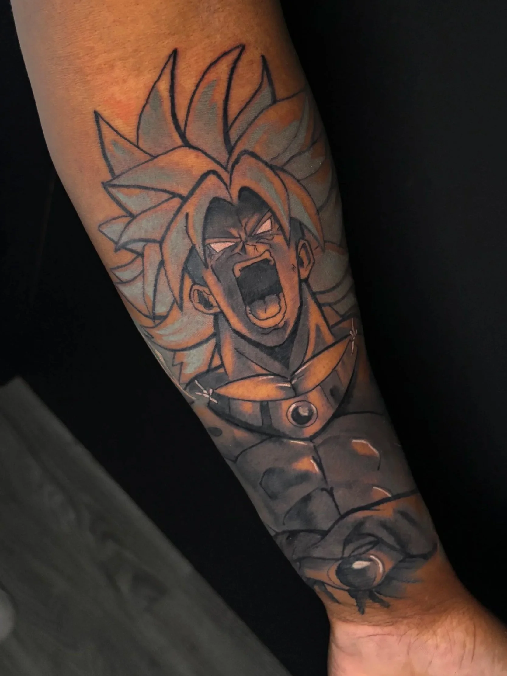 Tattoo of Broly from Dragon Ball Z on a person's arm, with a dynamic expression and detailed shading.