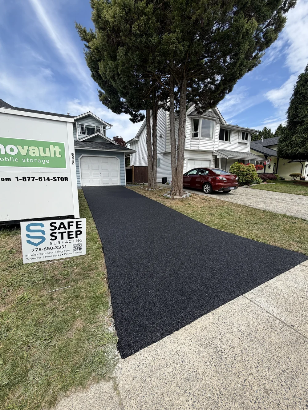 Black rubber driveway beside a front lawn
