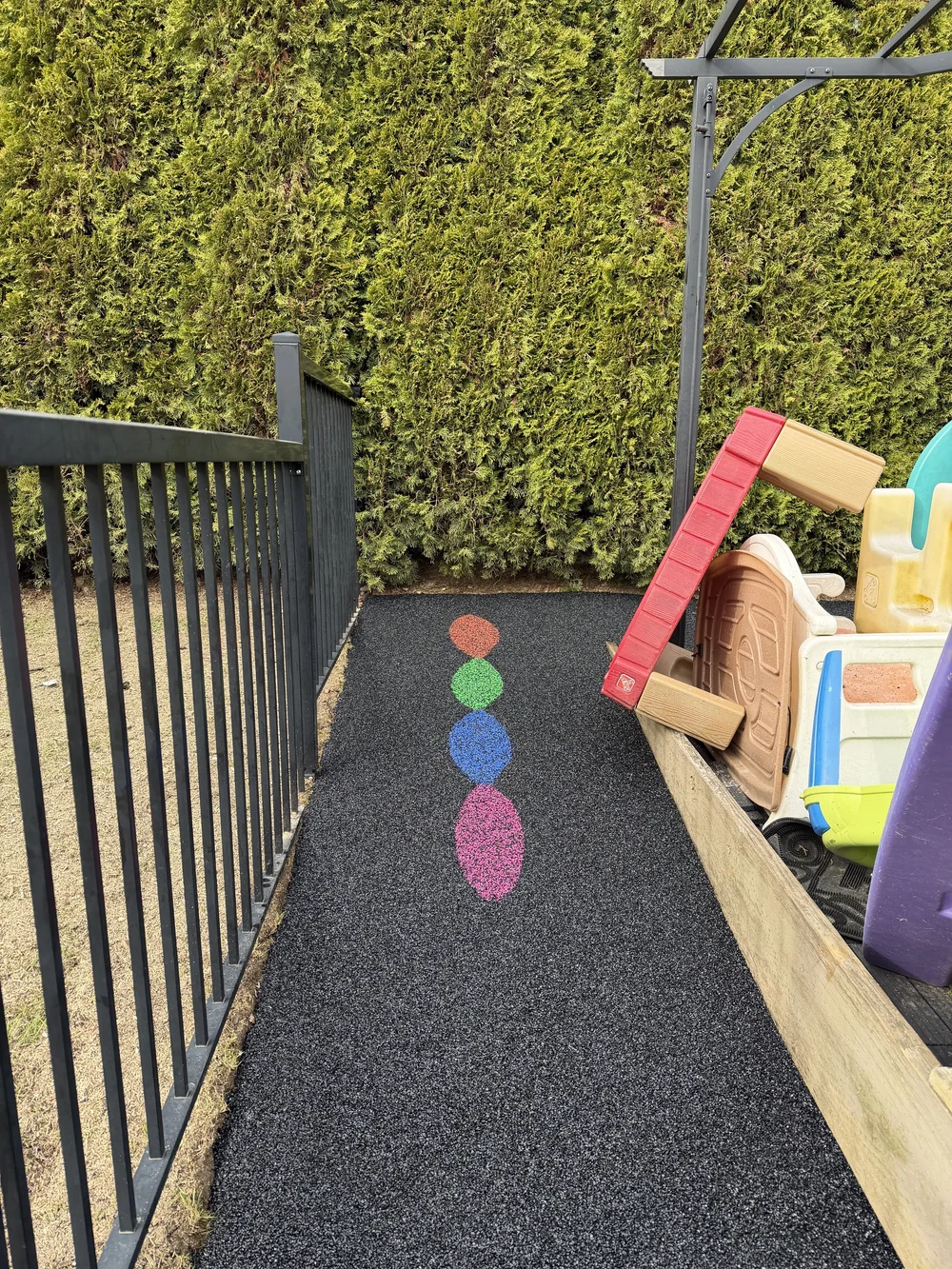 Seamless rubber playground safety surfacing with colourful circular markings and playhouse