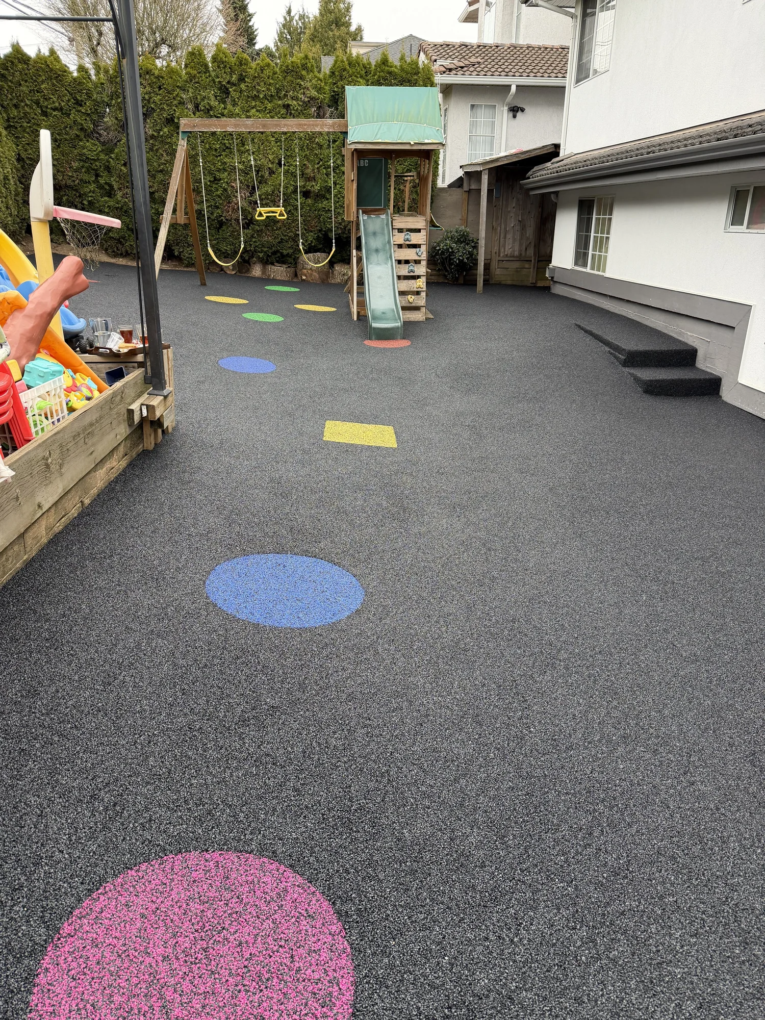 Daycare playground with colourful rubber safety surfacing, slides, swings, and climbing equipment