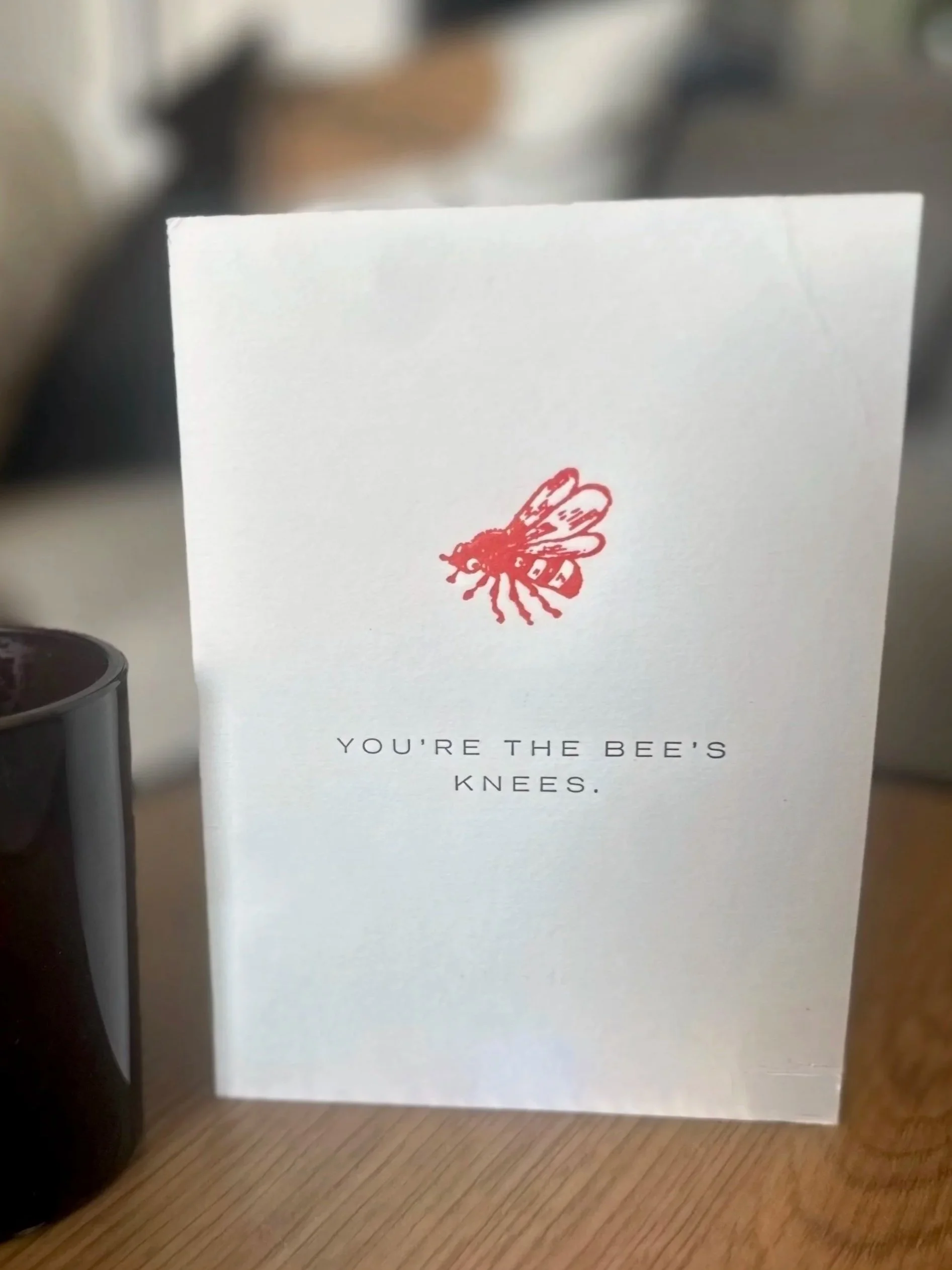 A white card with a red bee illustration and the text 'You're the bee's knees' in black font.