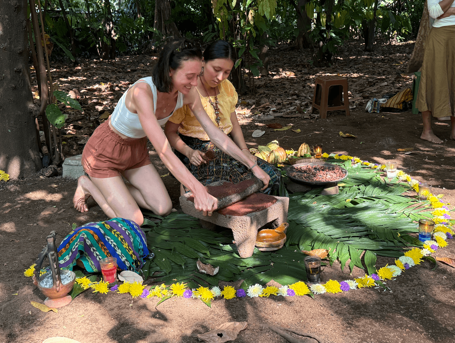 Traditional stone grinding of cacao beans on a metate during a ceremonial cacao preparation in nature.