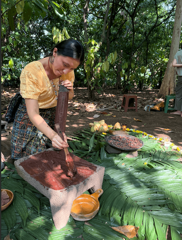 Freshly ground cacao paste being rolled on a stone metate as part of traditional ceremonial cacao making.