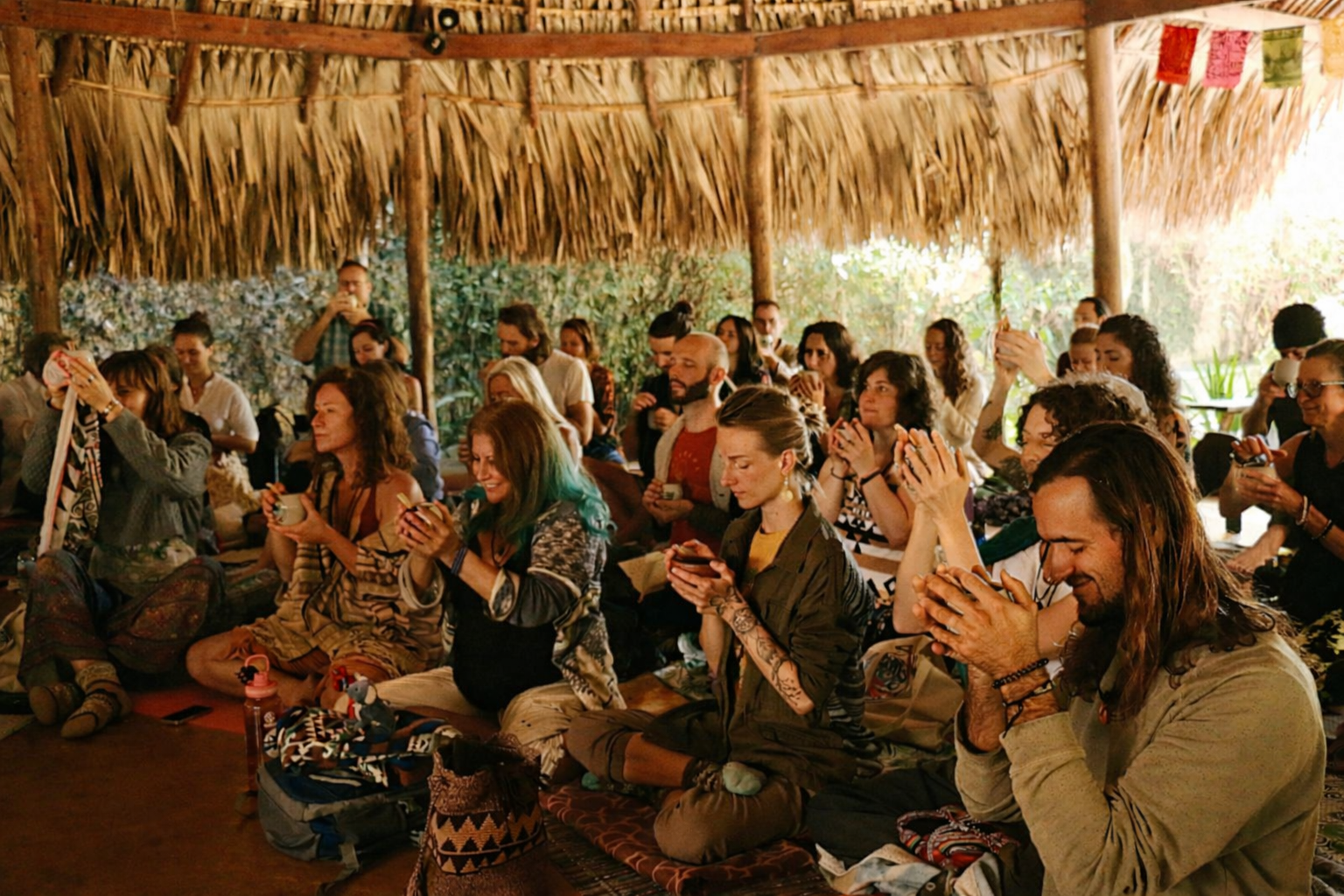 Group cacao ceremony with participants seated in circle holding ceremonial cups
