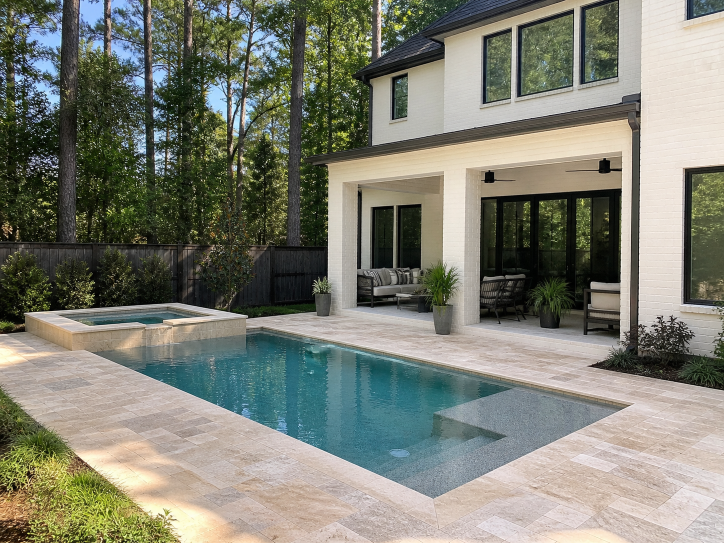 Backyard with a modern house, white brick exterior, outdoor seating, potted plants, a rectangular swimming pool, and a privacy fence surrounded by trees.