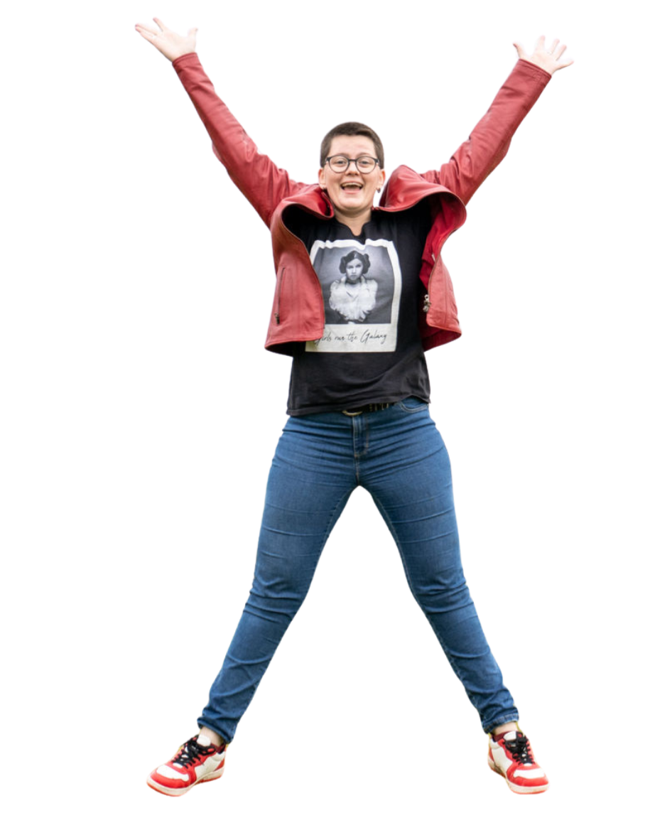 Freudestrahlende Person in Jeans, rotem Jacke und T-Shirt mit einem Bild von Emilie in Schwarz-Weiß, mit ausgebreiteten Armen gegen schwarzen Hintergrund.