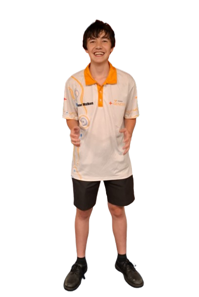 A young boy with short brown hair smiling, wearing an orange and white sports jersey, black shorts, and black shoes, standing with thumbs up.