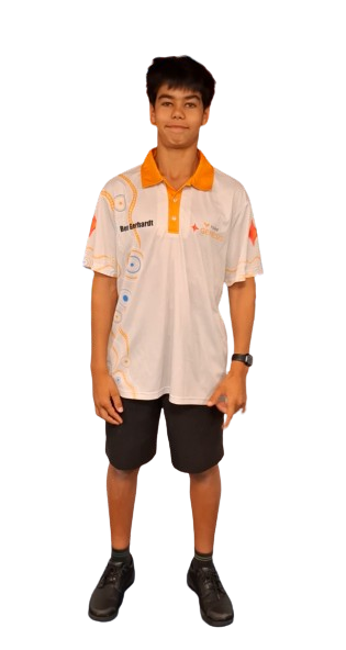 A young boy standing and smiling, wearing a white and orange sports polo shirt and black shorts.
