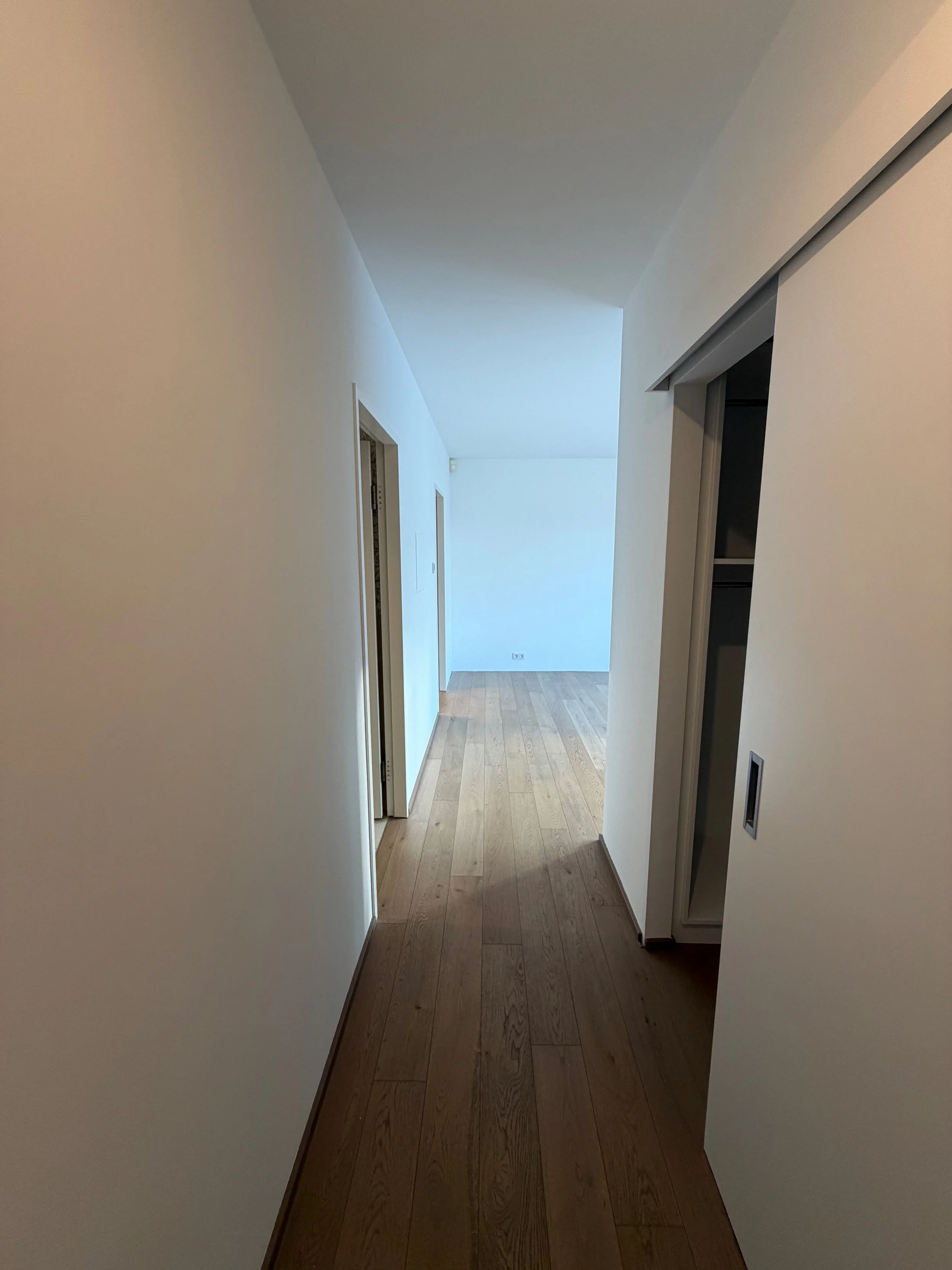 Leere Flur in einem modernen, weißen Apartment mit Holzboden.