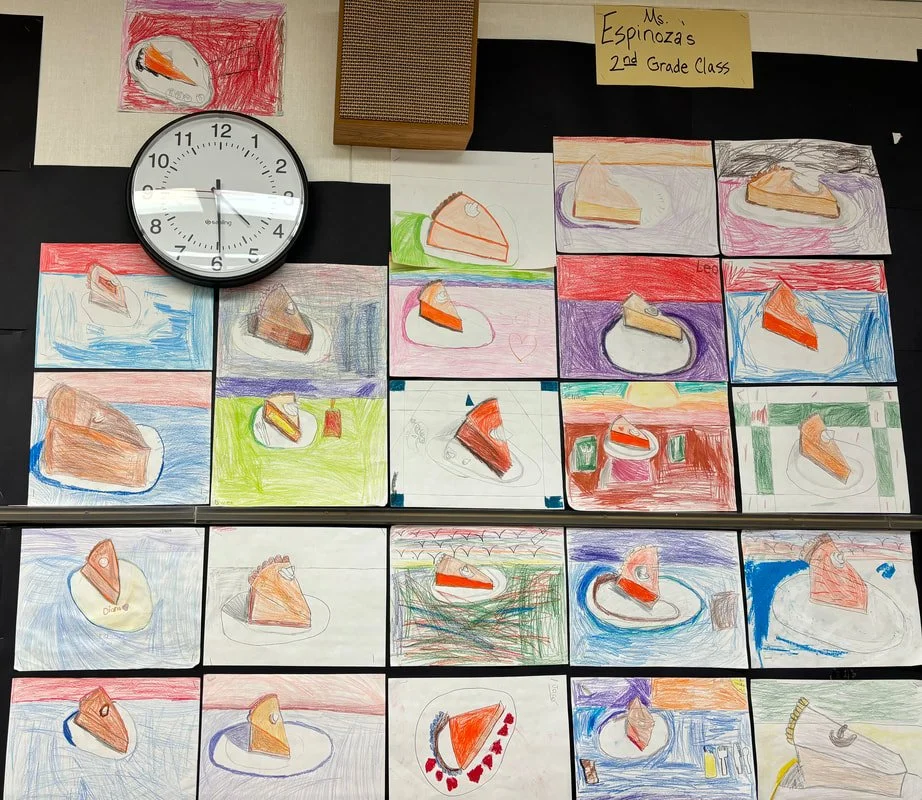 A display of children's drawings of a slice of pumpkin pie on various colored backgrounds, labeled as Ms. Espinoza's 2nd Grade Class. There is a clock showing 9:00, a small wooden box, and a sign indicating the class.