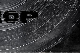 Close-up of a vinyl record with a black and gray surface and partial black text reading 'rap'.