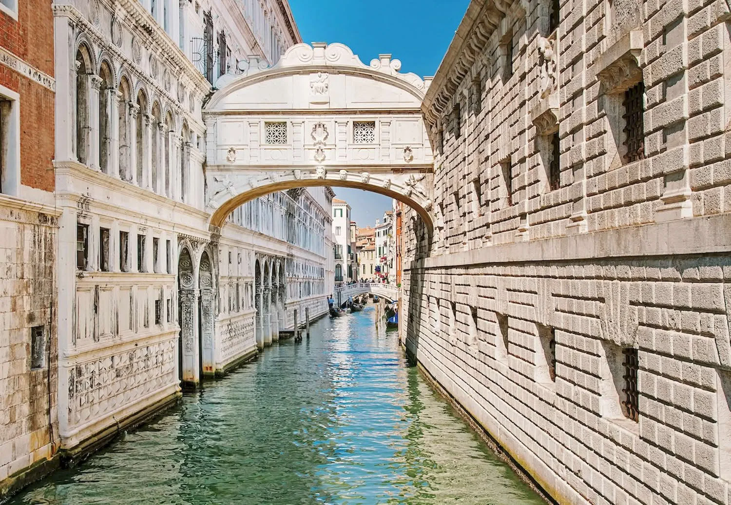 Kanal in Venedig mit historischen Gebäuden und Brücken bei sonnigem Wetter.