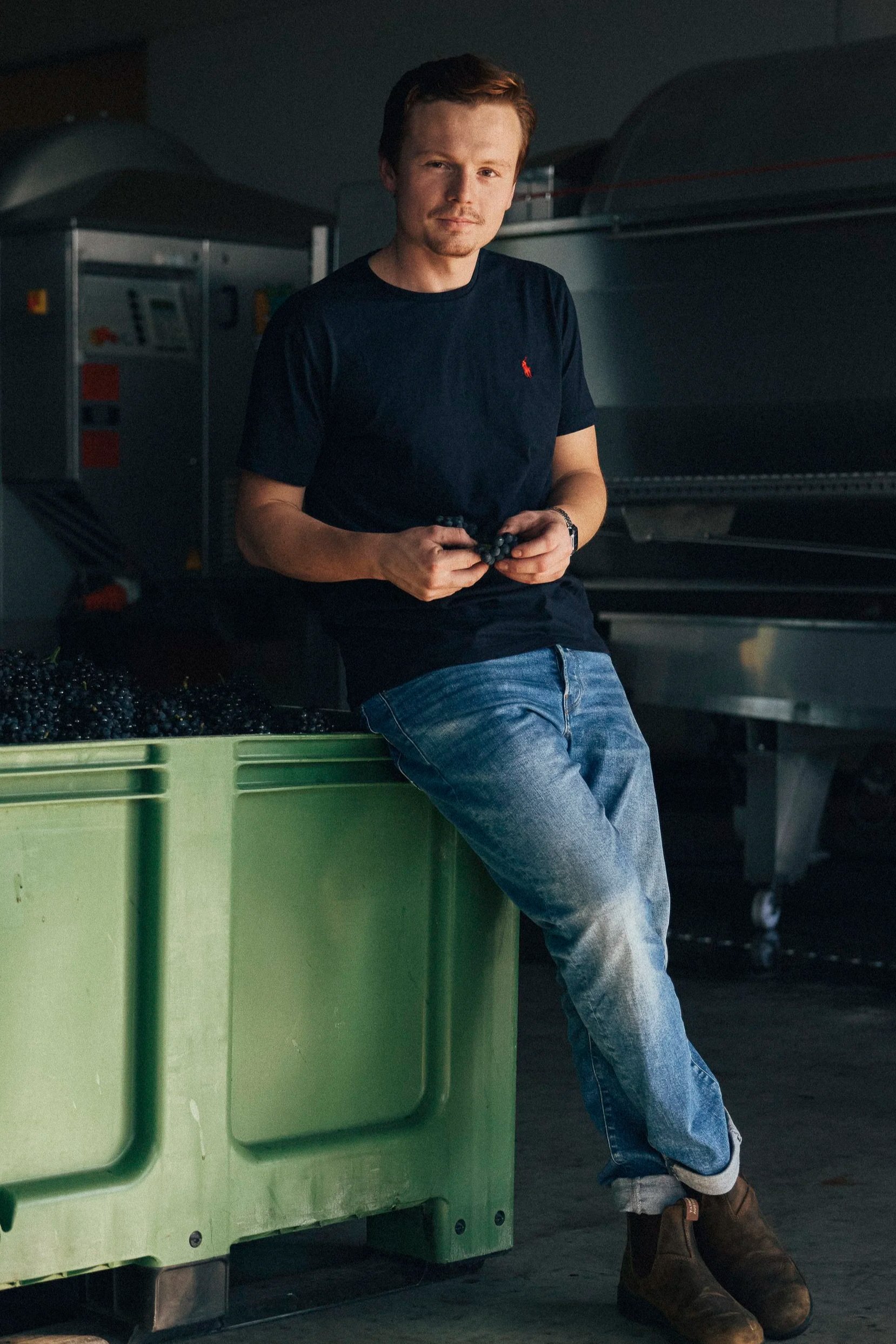 Xaver Kranz lehnt an einer Box mit Trauben. Spätburgunder aus der VDP.Erste Lage.