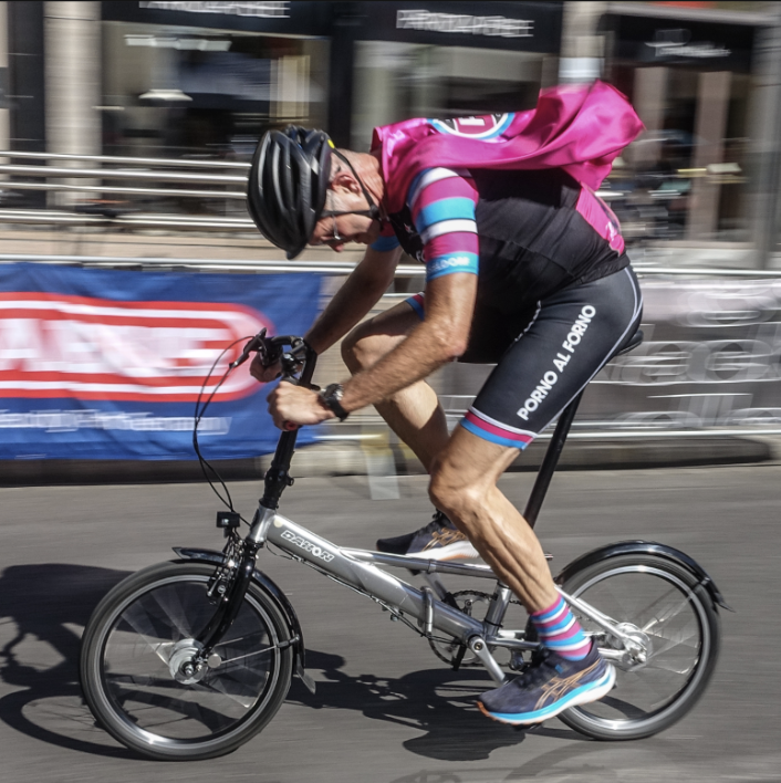 Mensch in Fahrradkleidung mit Helm fährt auf einem Fahrrad, während er an einem Rennen teilnimmt.