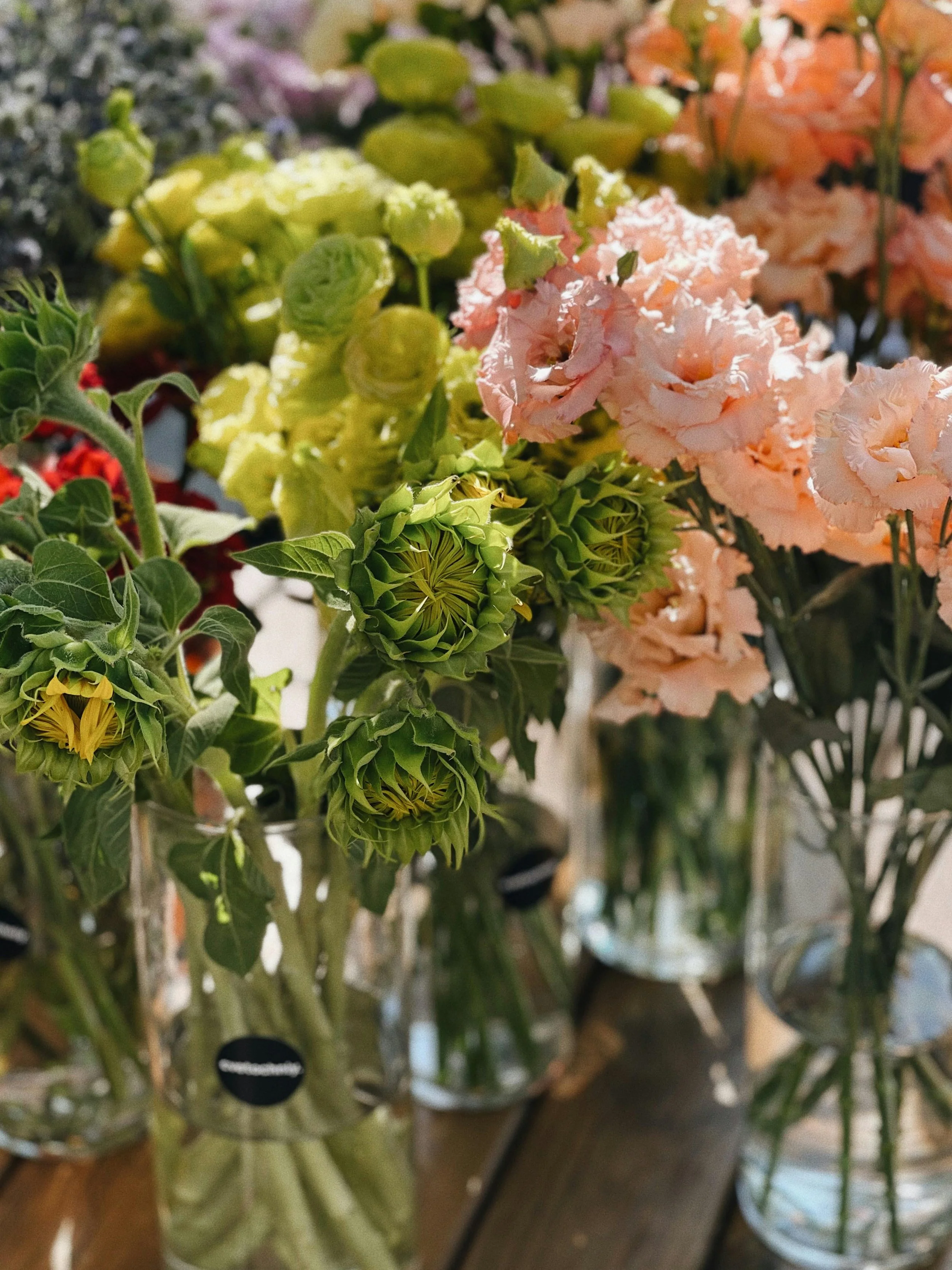 Close-up of various colorful flowers, including pink, yellow, and green, displayed in a vase or floral arrangement.