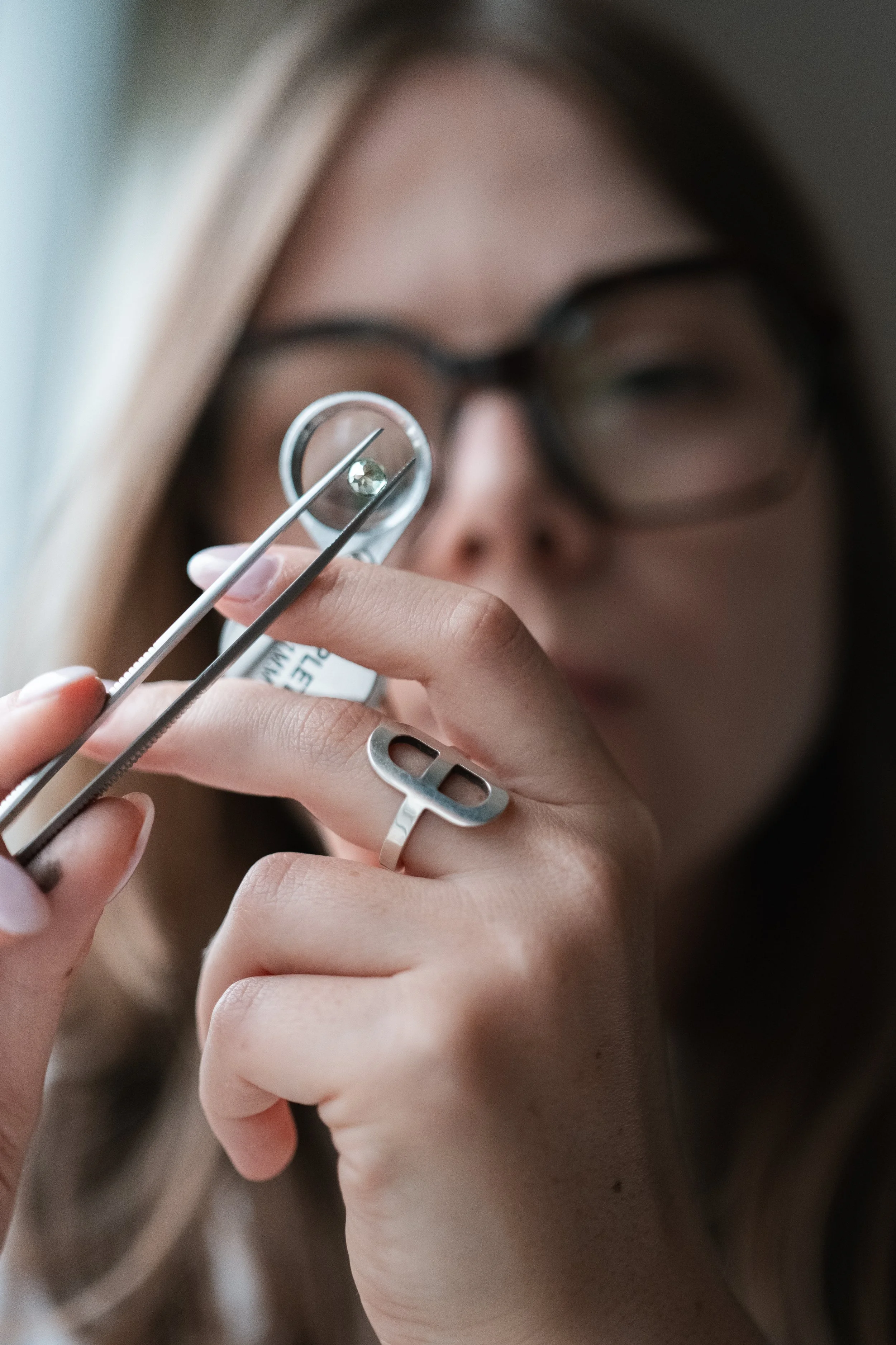 Une femme portant des lunettes effectue une intervention ophtalmologique avec un instrument chirurgical, concentrée sur l'œil.