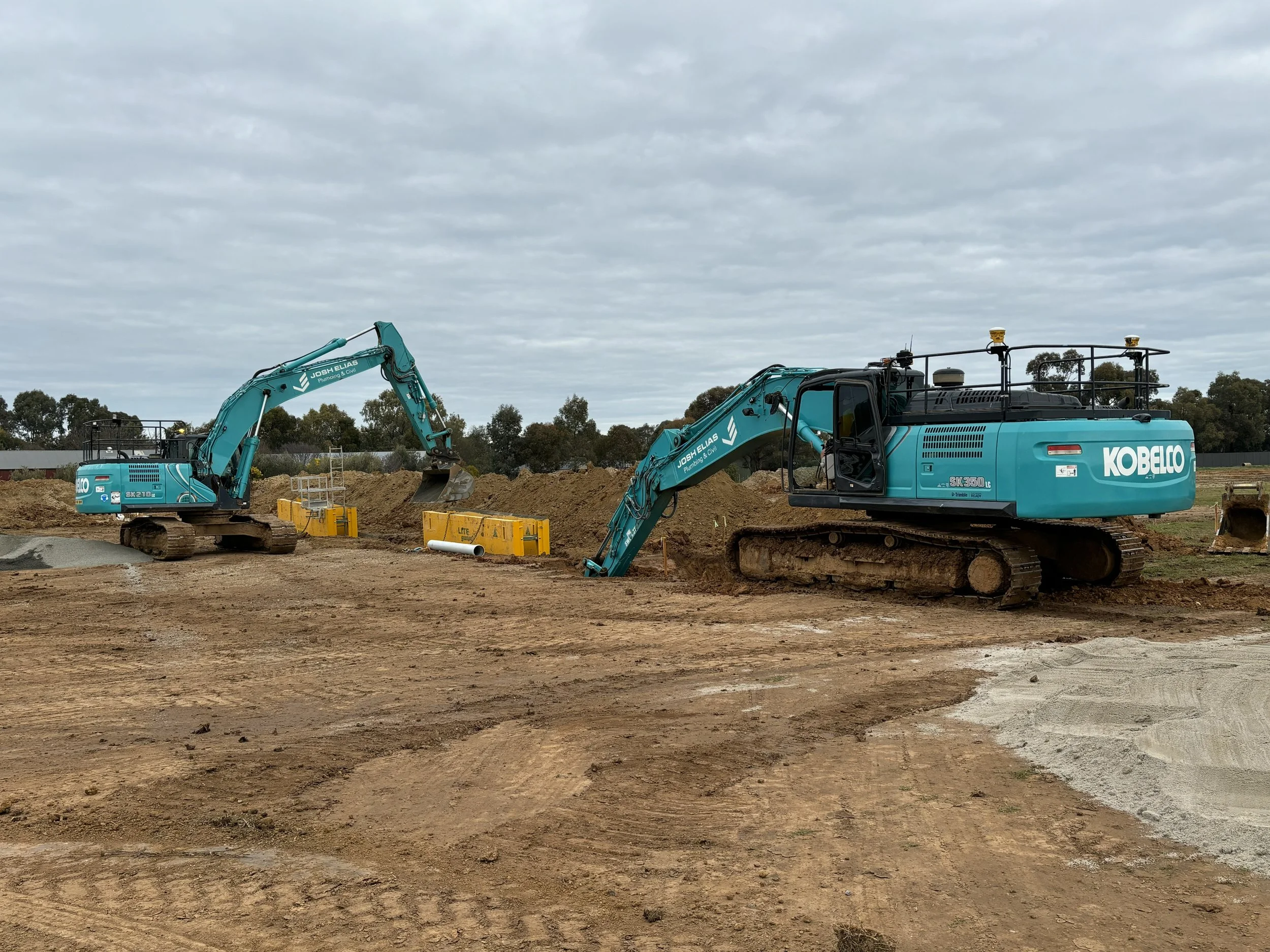 Two JEPC excavators working on a construction site, digging and moving dirt