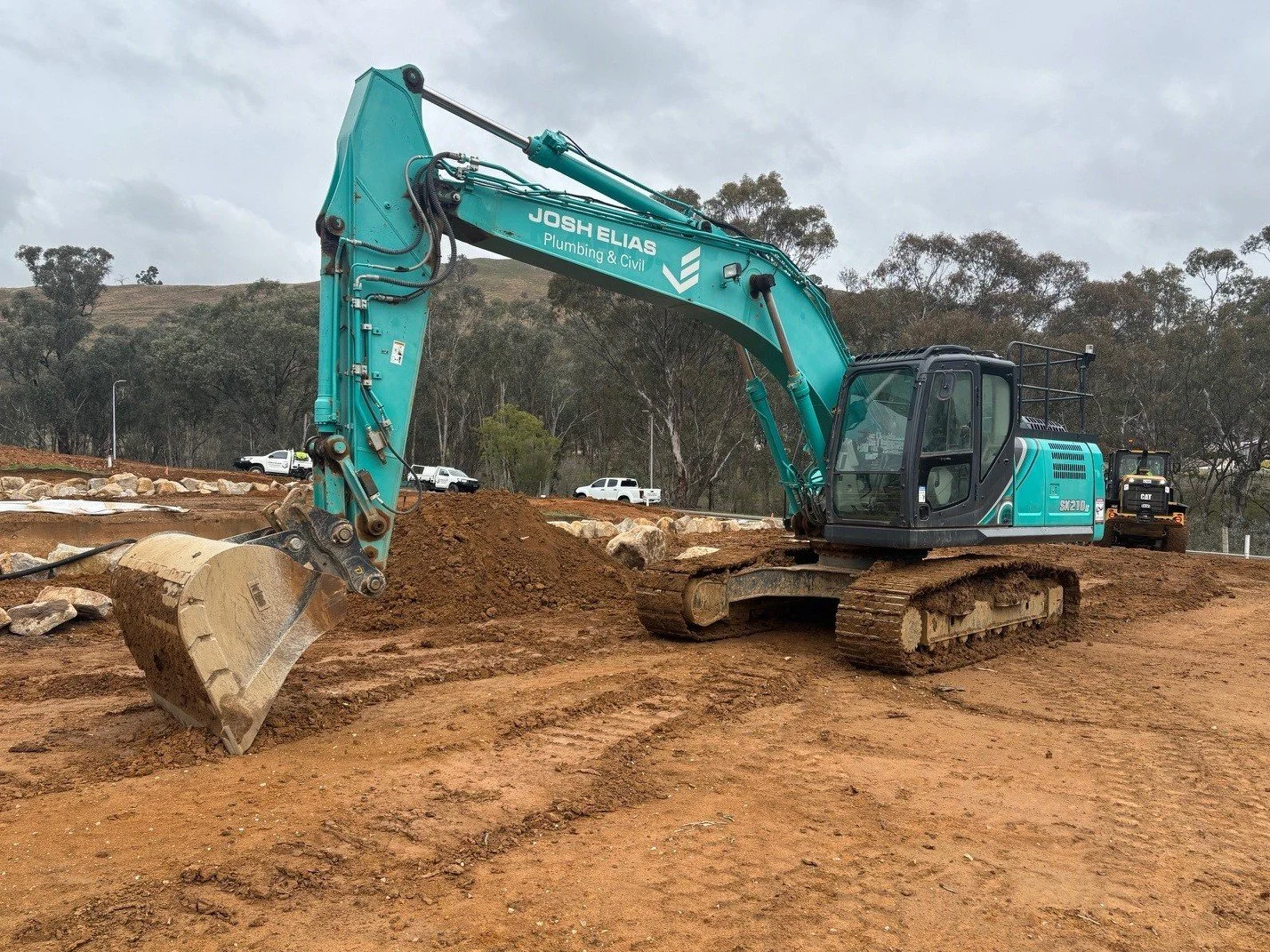 A blue excavator on a construction site moving dirt with a scoop.