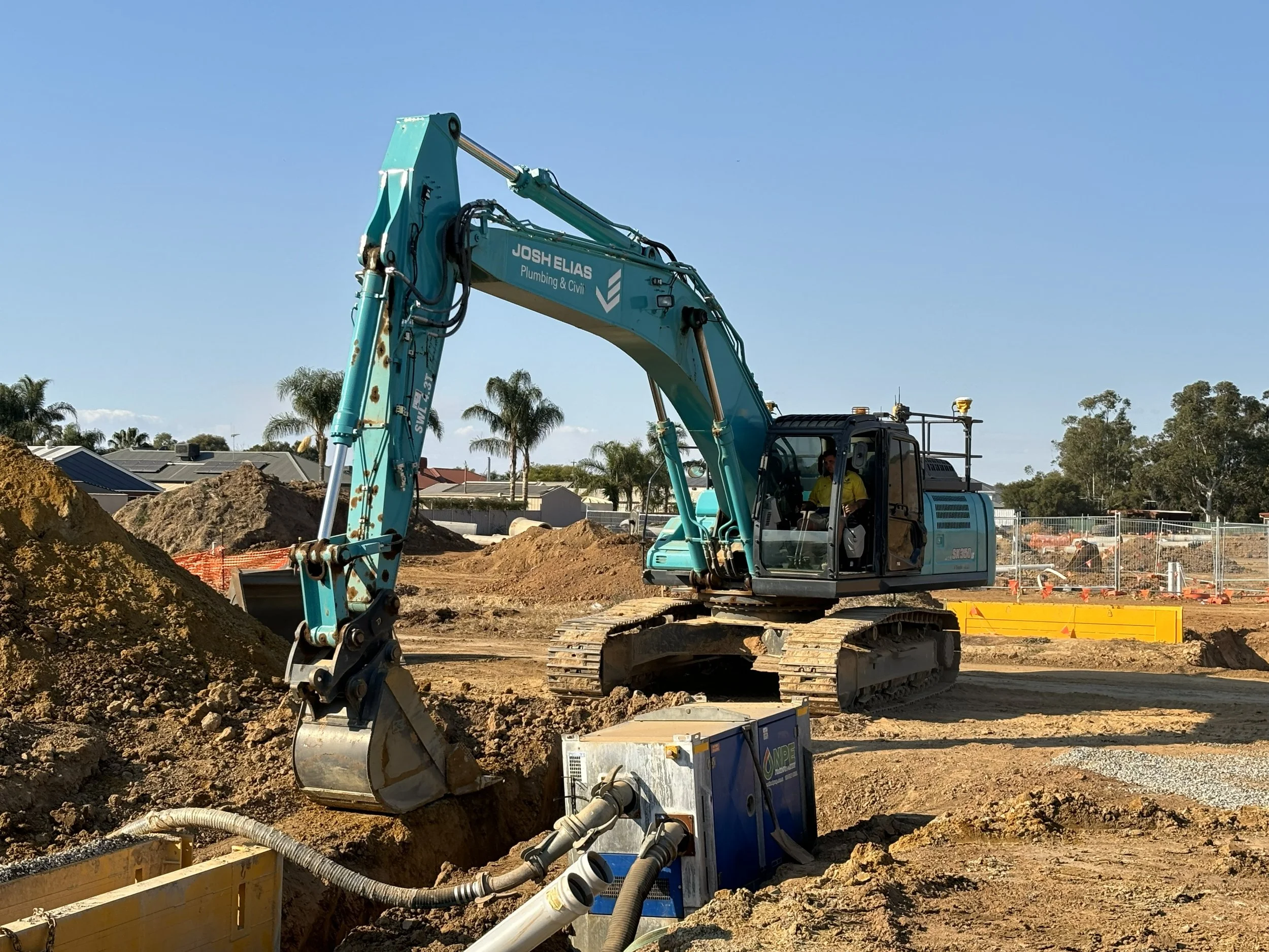 A JEPCexcavator digging in a construction site with dirt mounds