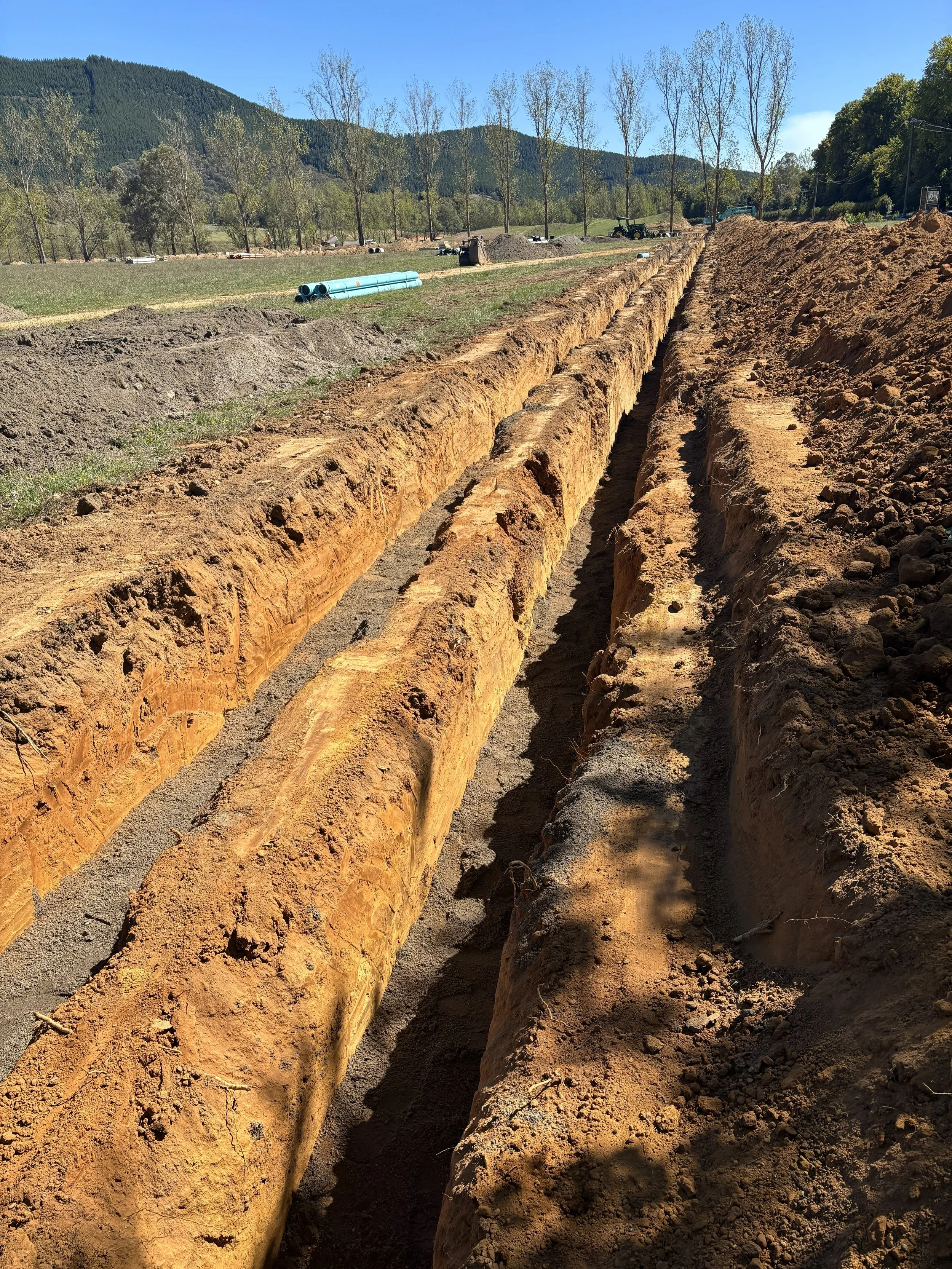 Long trench being dug for pipeline construction in a rural area