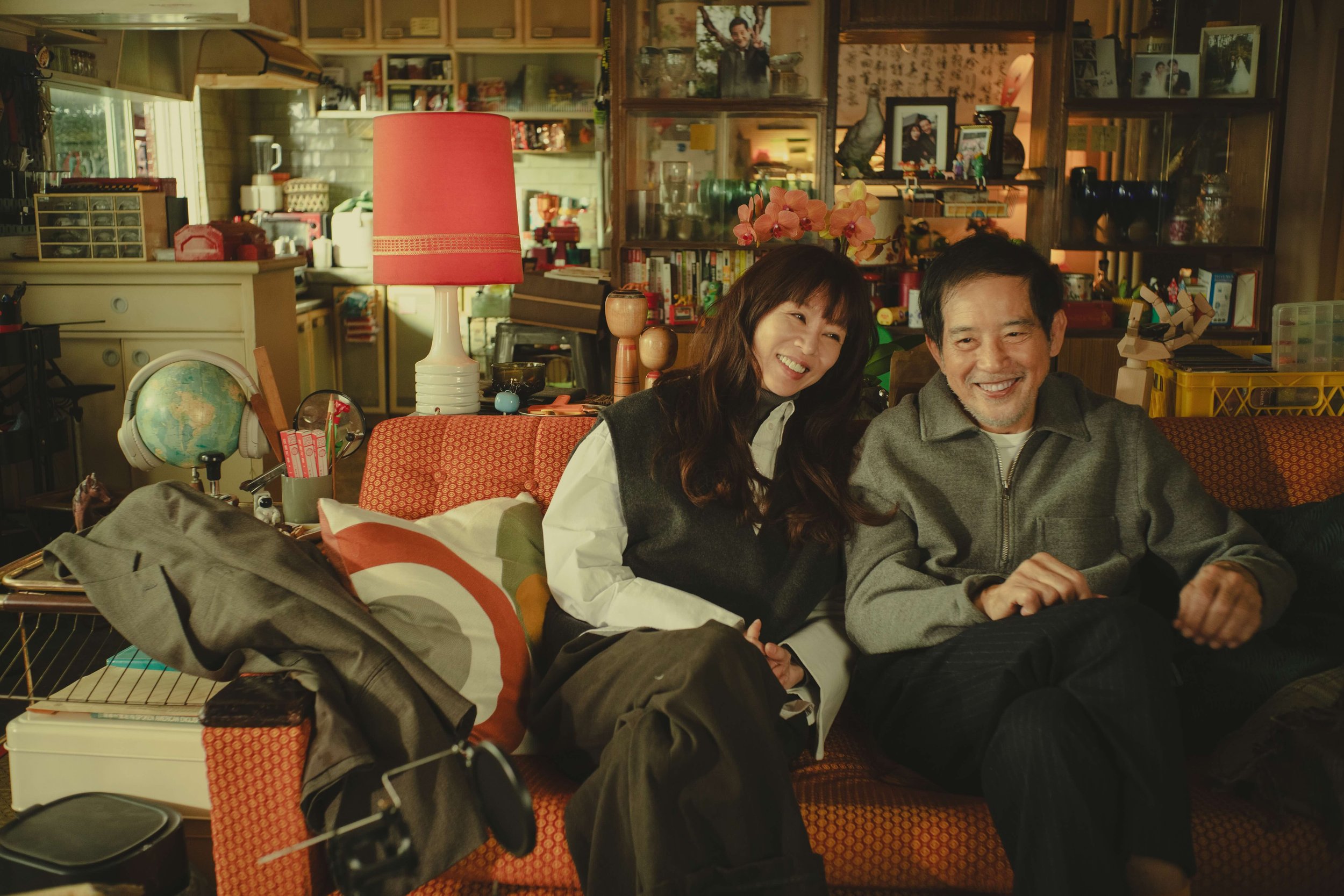 Intimate campaign still from Forget You Not showing two lead characters seated together in a warm, lived-in home environment, emphasizing emotional connection and everyday intimacy.