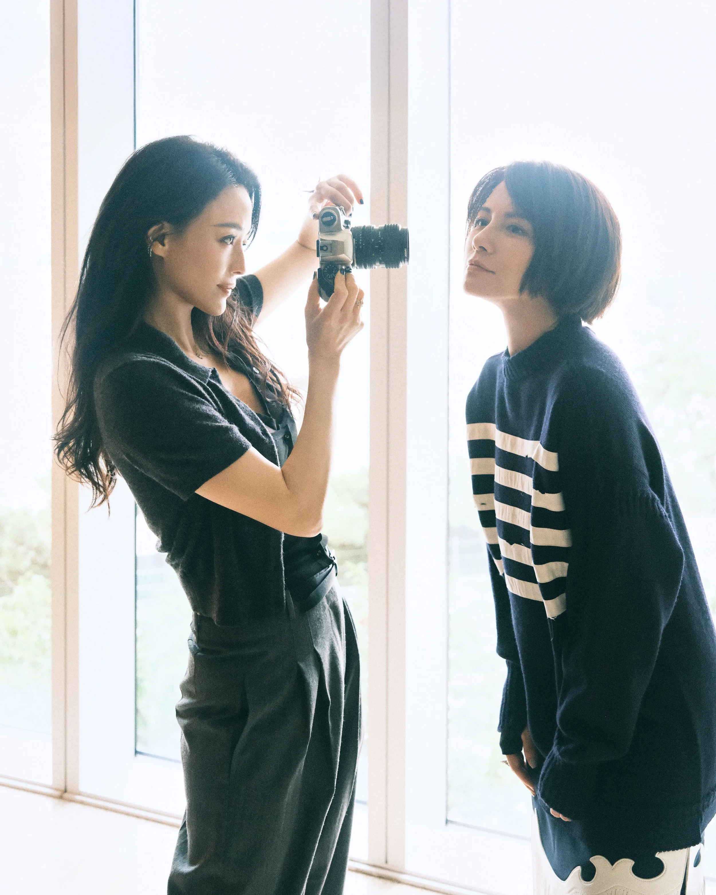 A behind-the-scenes creative moment with two actors using a camera at the 2025 Busan International Film Festival.