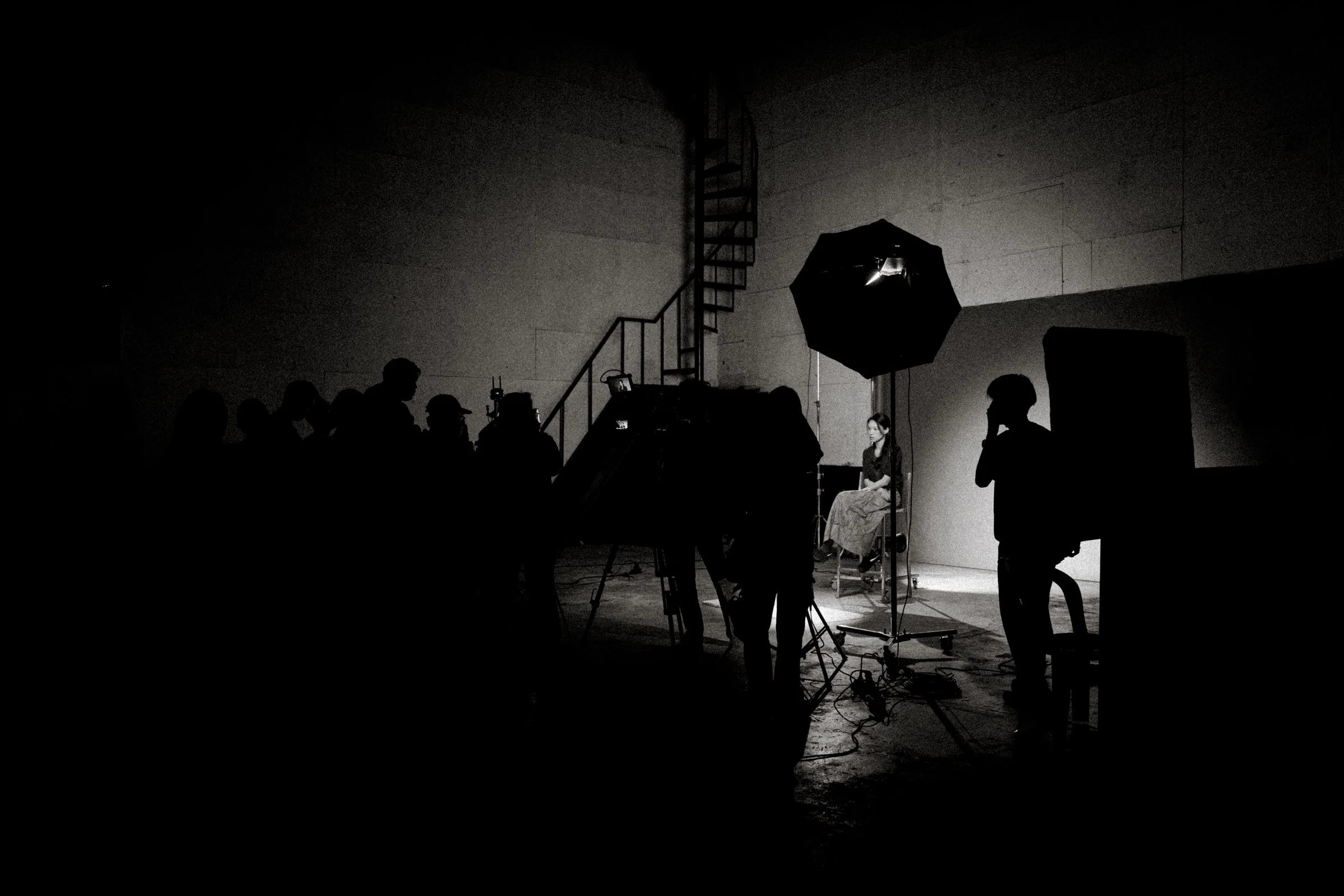 Behind-the-scenes studio setup with lighting equipment and crew photographing talent on set.