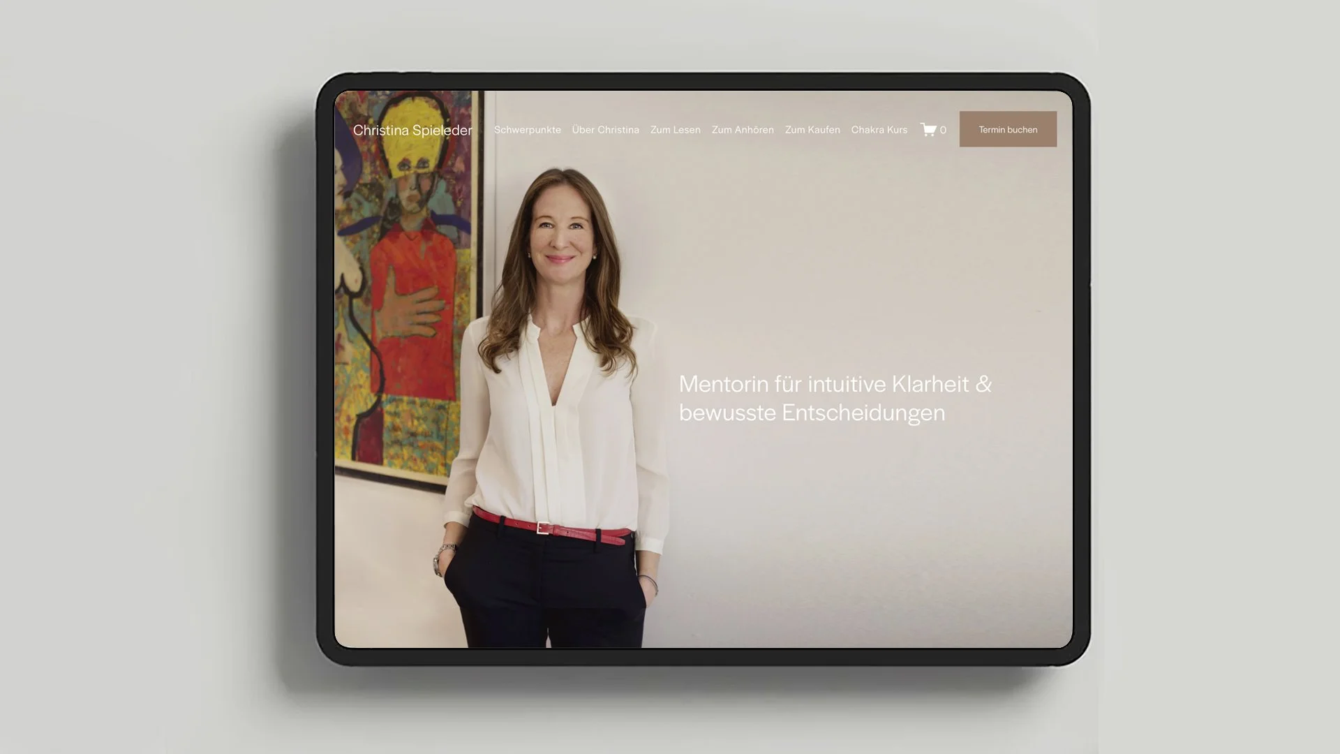 Foto einer Frau in einem weißen Hemd und schwarzen Hosen, die vor einem weißen Hintergrund steht, mit einem gemalten Bild im Hintergrund. Text auf der Website besagt, dass sie Mentorin für intuitive Klarheit und bewusste Entscheidungen ist.
