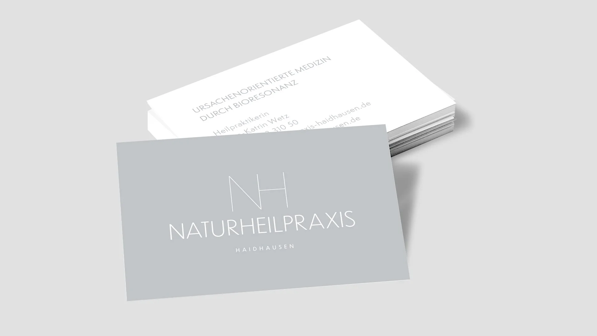 Visitenkarte für eine Naturheilpraxis mit hellgrauem Hintergrund und weißem Text, die Praxis heißt 'NATURHEILPRAXIS HAIDHAUSEN'.