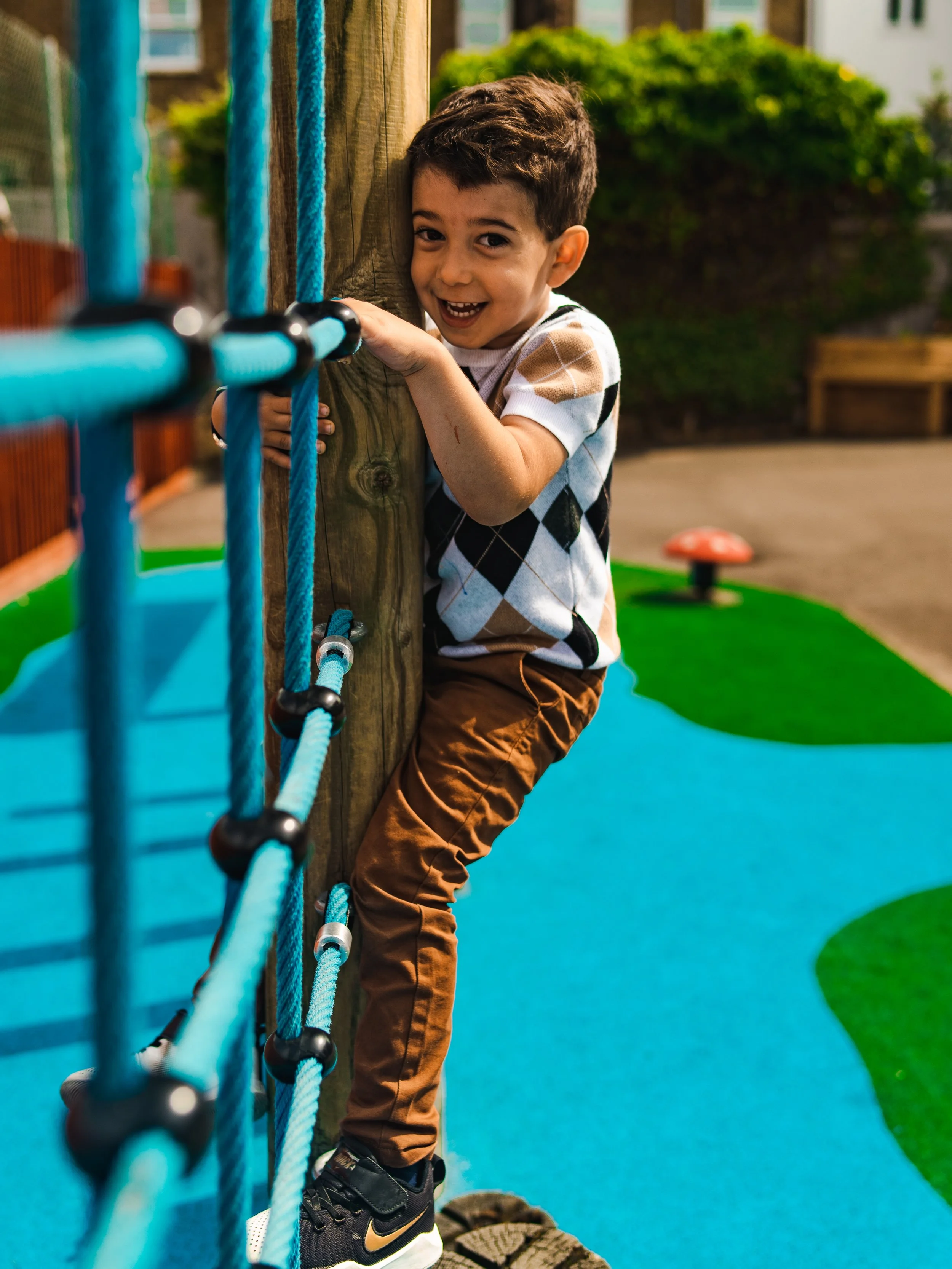 Young boy climbing on a rope wall climbing frame at Global Camps holiday camp