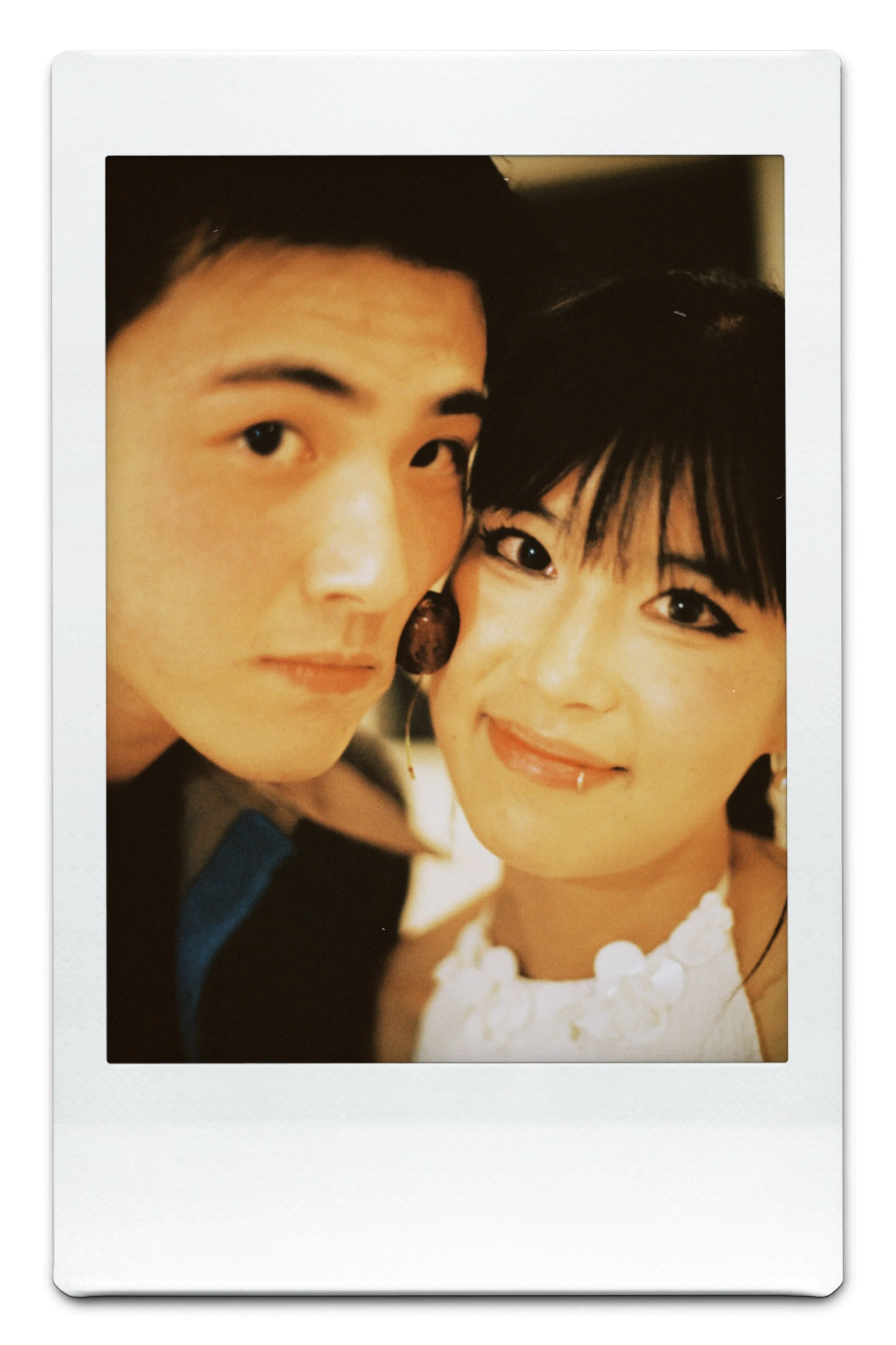 A close-up polaroid photo of a young man and woman smiling, with only part of their faces visible, set in a white border.