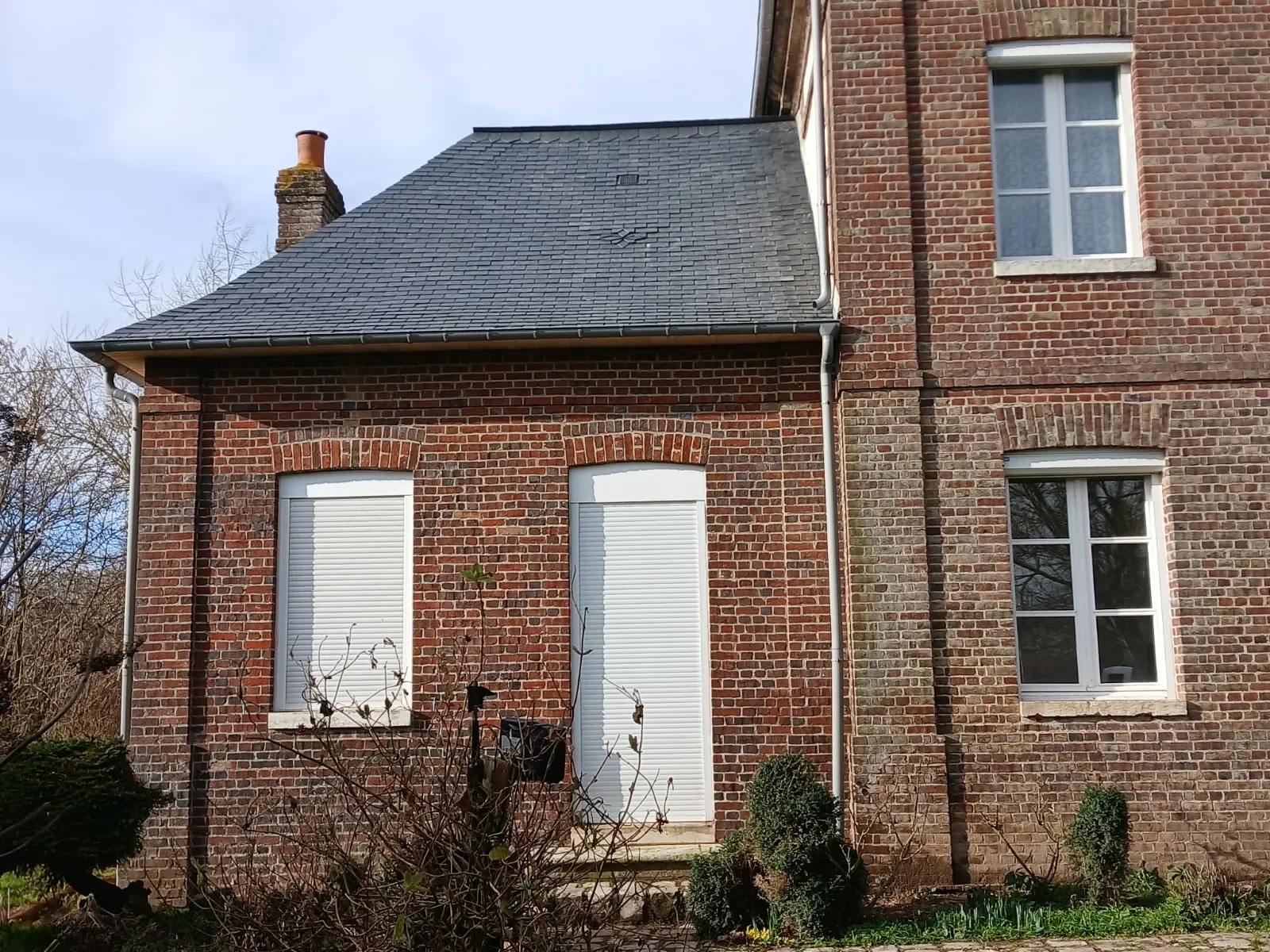 Détail d'une couverture en ardoise naturelle sur une aile en brique, chantier de couvreur en Seine-Maritime