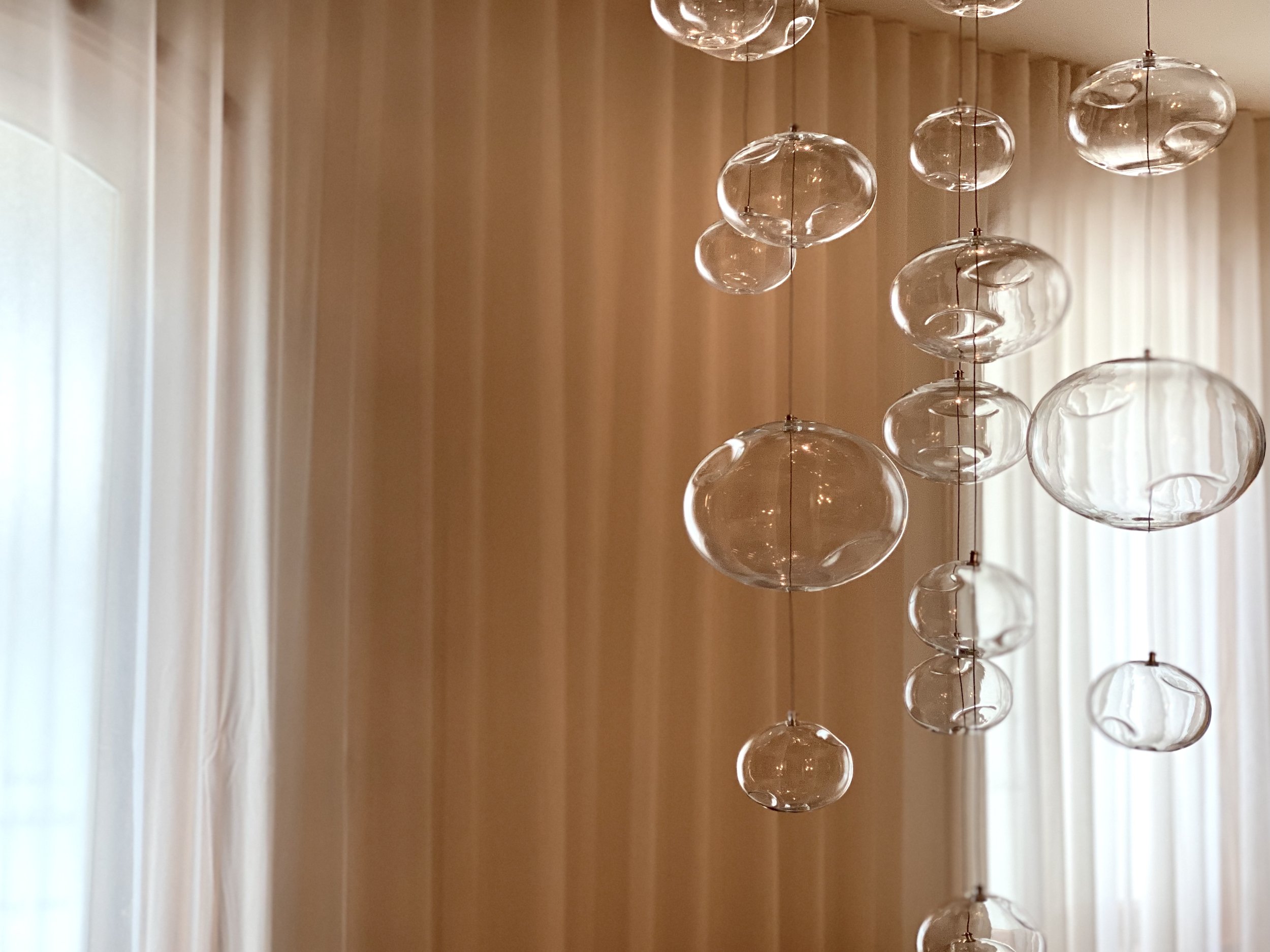 Hängande glasdekoration framför beige gardin