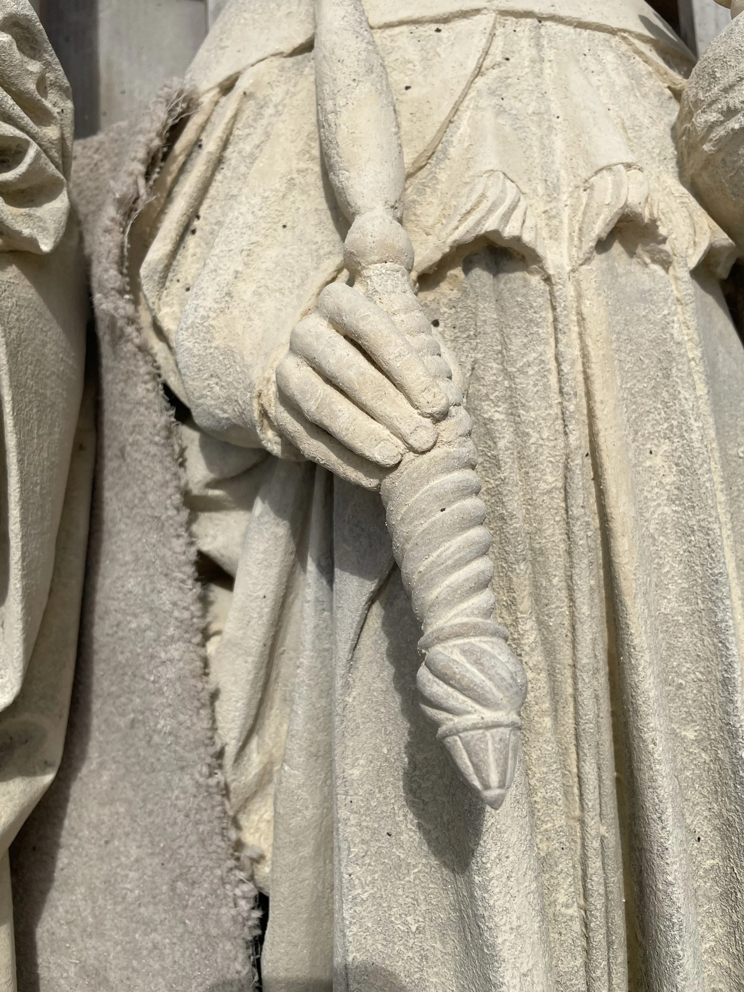 Close-up of a carved stone sculpture depicting a person holding a large, coiled shell.