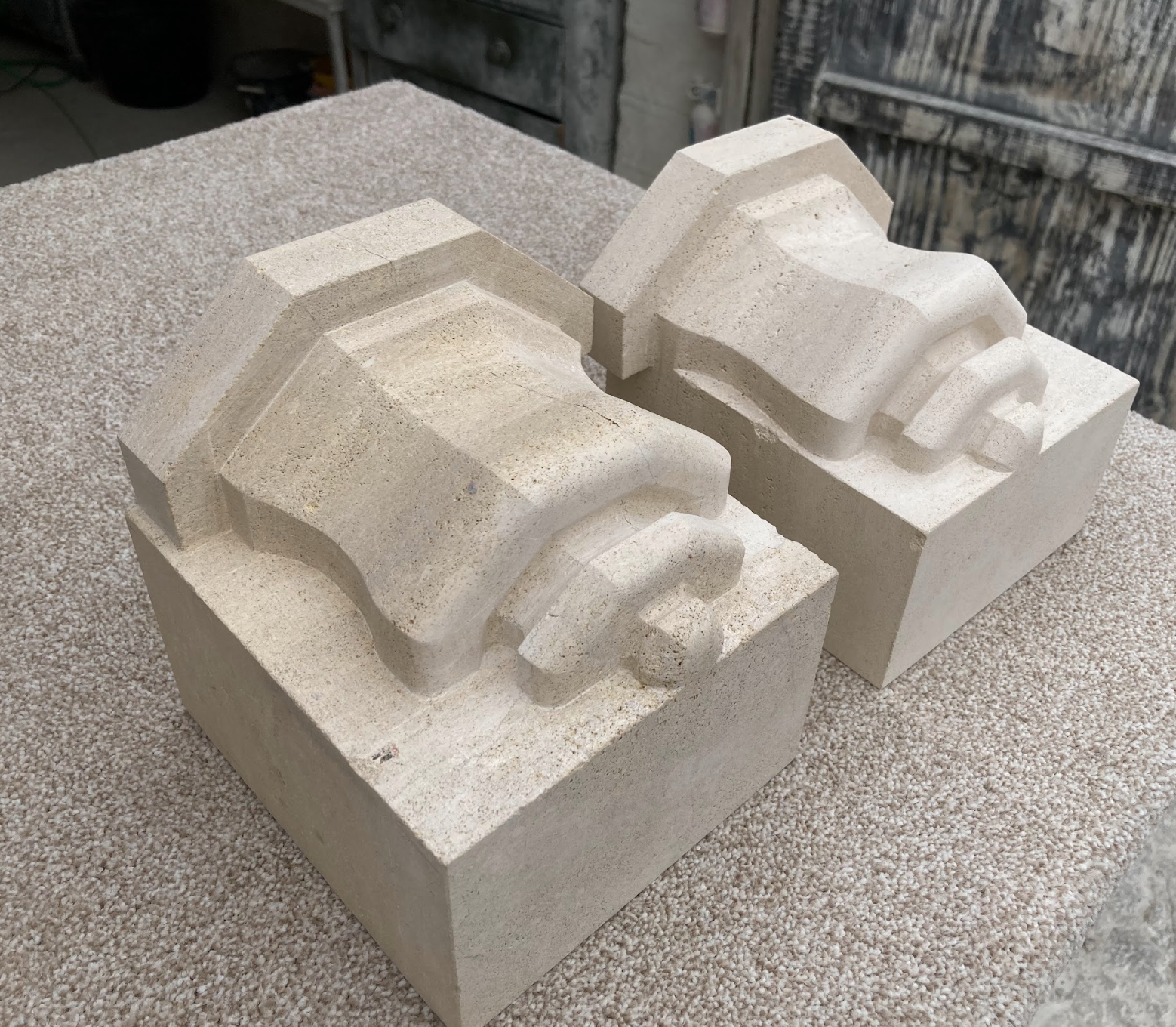 Two plaster molds of decorative architectural elements on a textured surface.