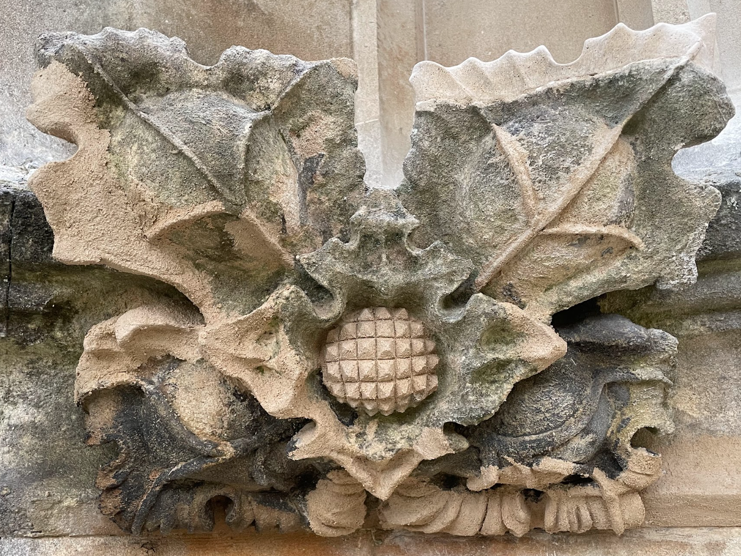 Close-up of an ornate stone carving depicting a stylized face with leaves and circular patterns.