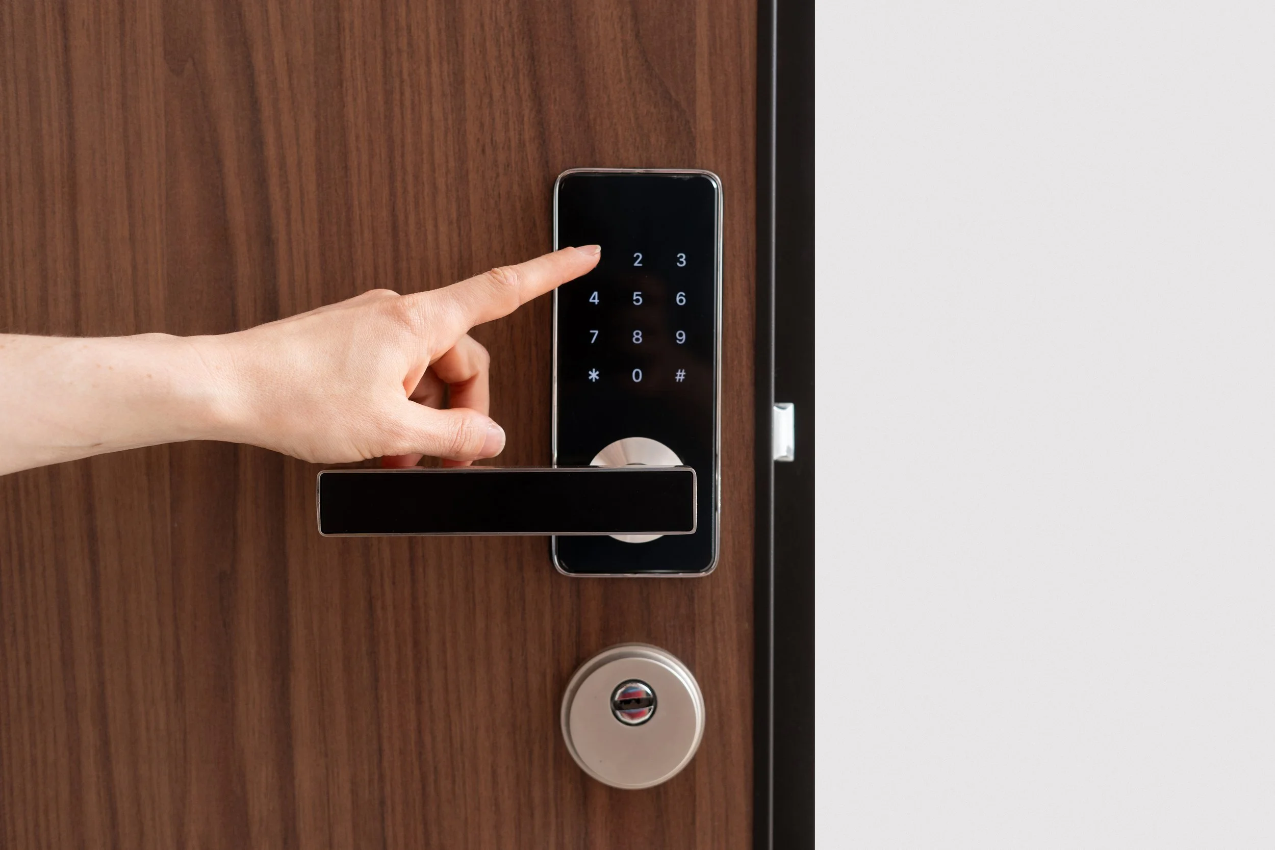 A person pressing a digital keypad lock on a wooden door.