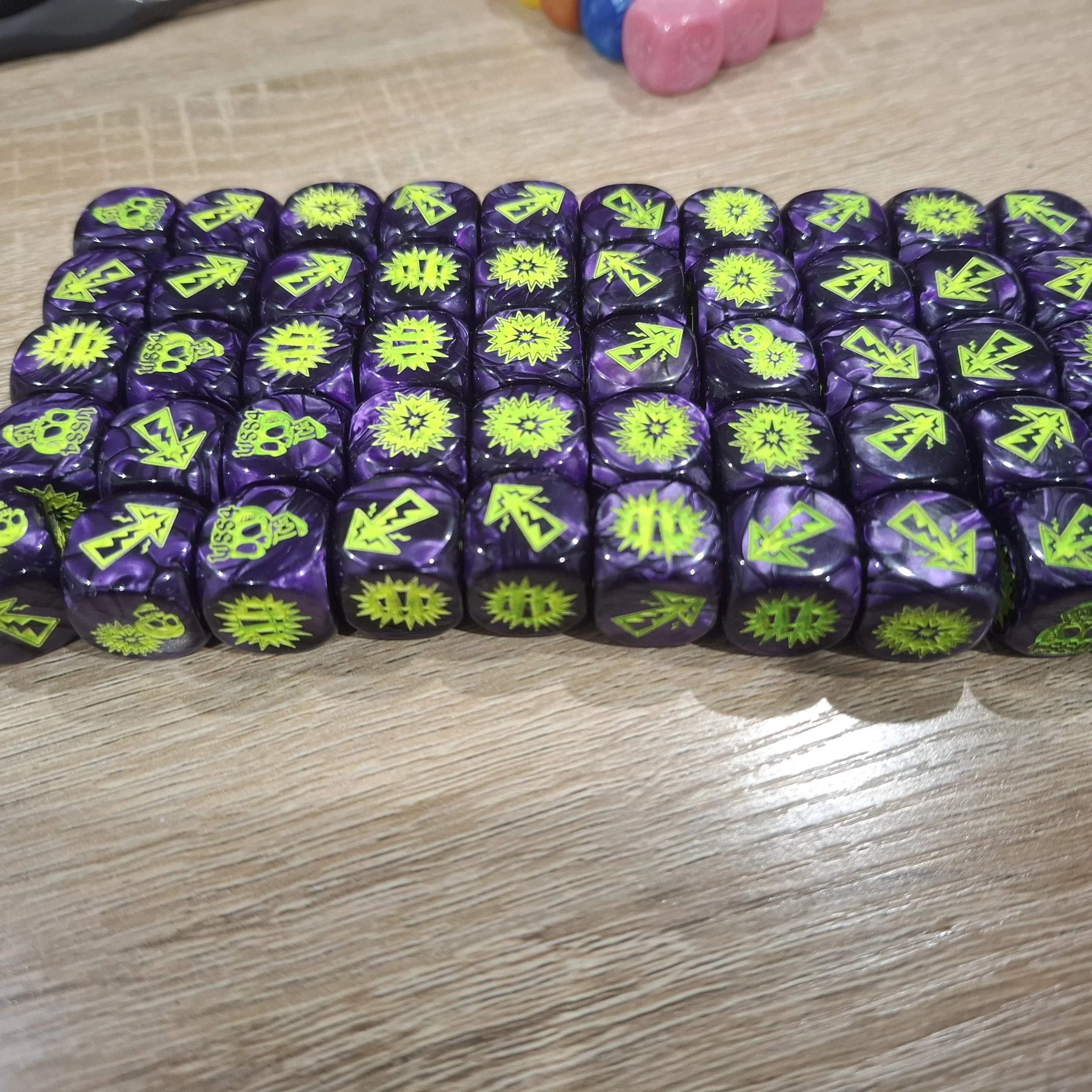 Close-up of multiple black dice with glowing green symbols and patterns, arranged in rows on a wooden surface.