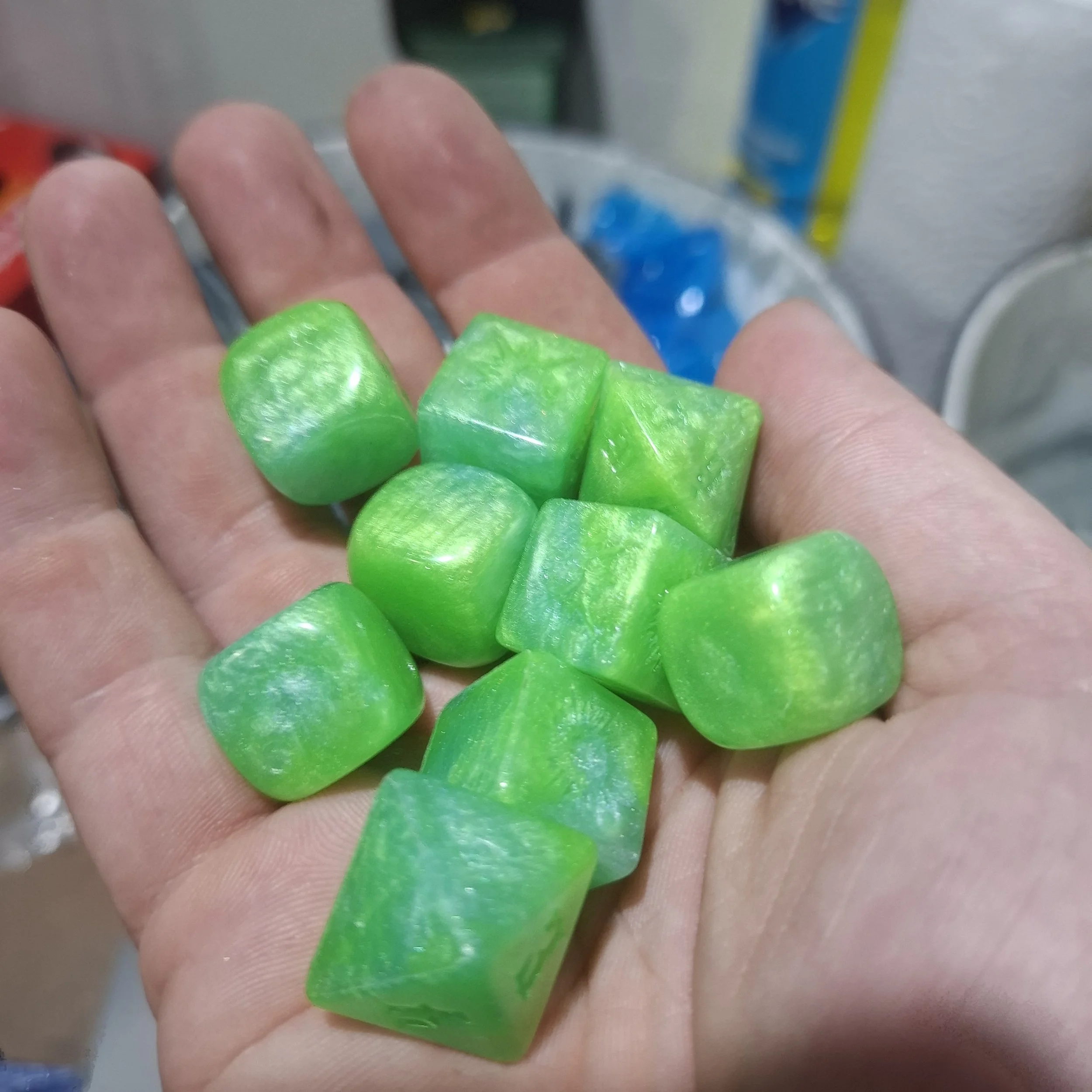 A hand holding several bright green, irregularly shaped stones or minerals with a smooth, shiny surface.