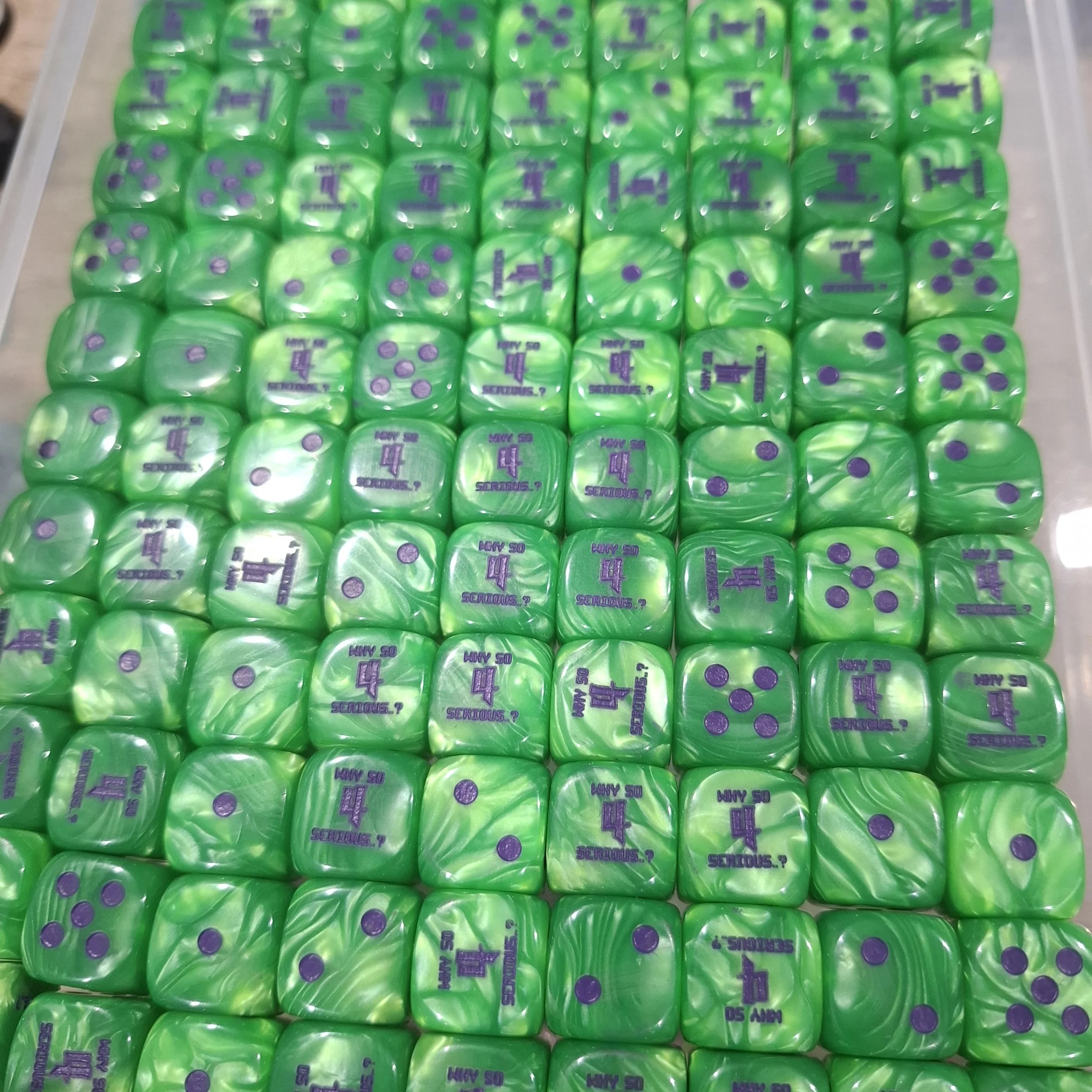 A large display of green and purple dice with printed messages, arranged in neat rows on a surface.